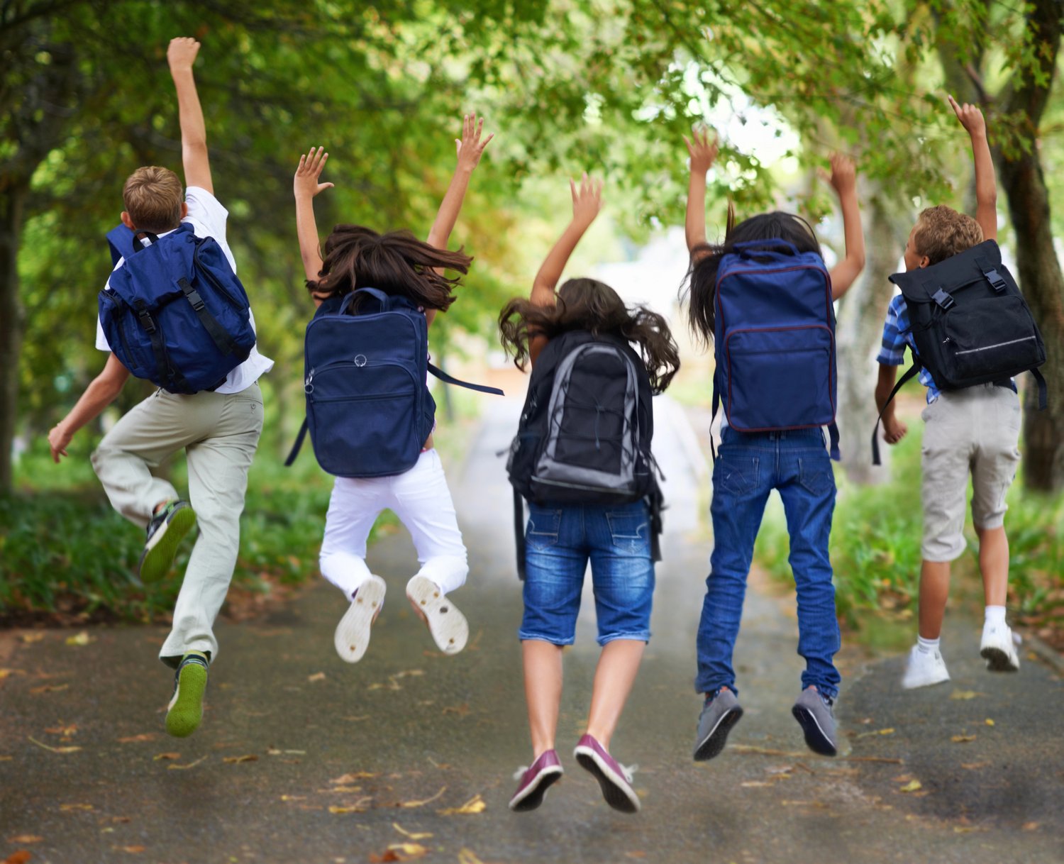 Middle school students jumping with backpacks, celebrating the end of the school year.