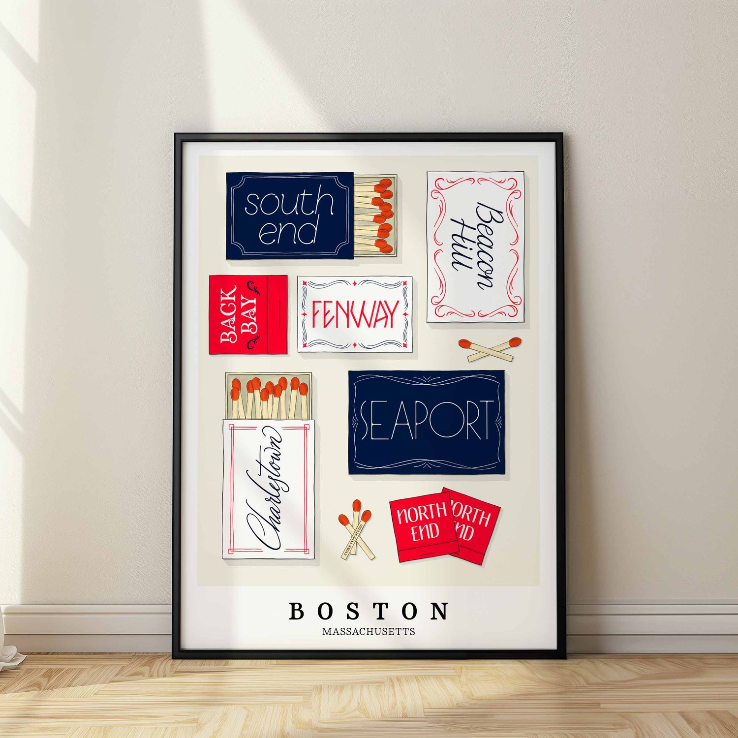 A framed picture of Boston, Massachusetts neighborhoods drawn in various lettering styles on matchboxes. Artwork has a red, white and blue color scheme
