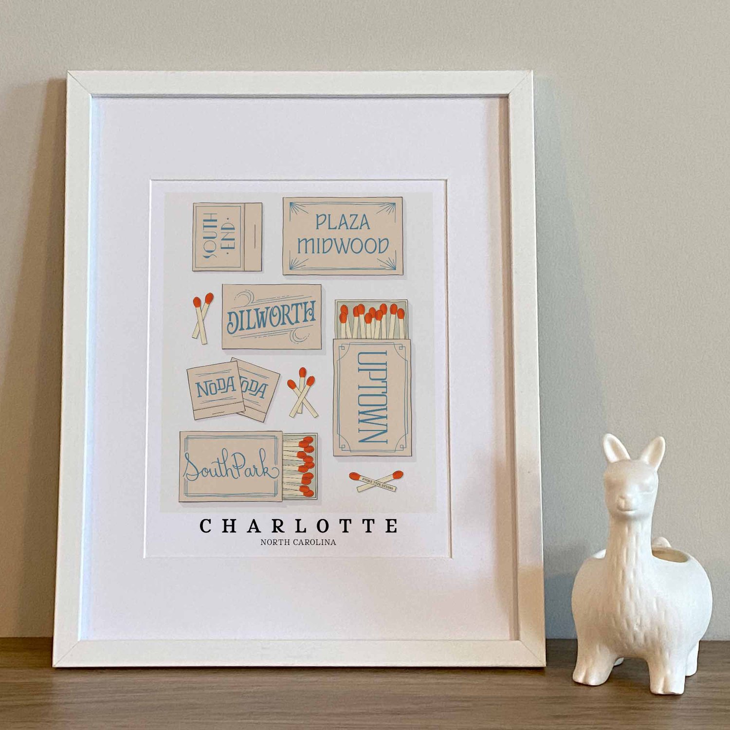 Hand-drawn Charlotte matchbox wall art featuring custom lettering in calming beige and blue tones