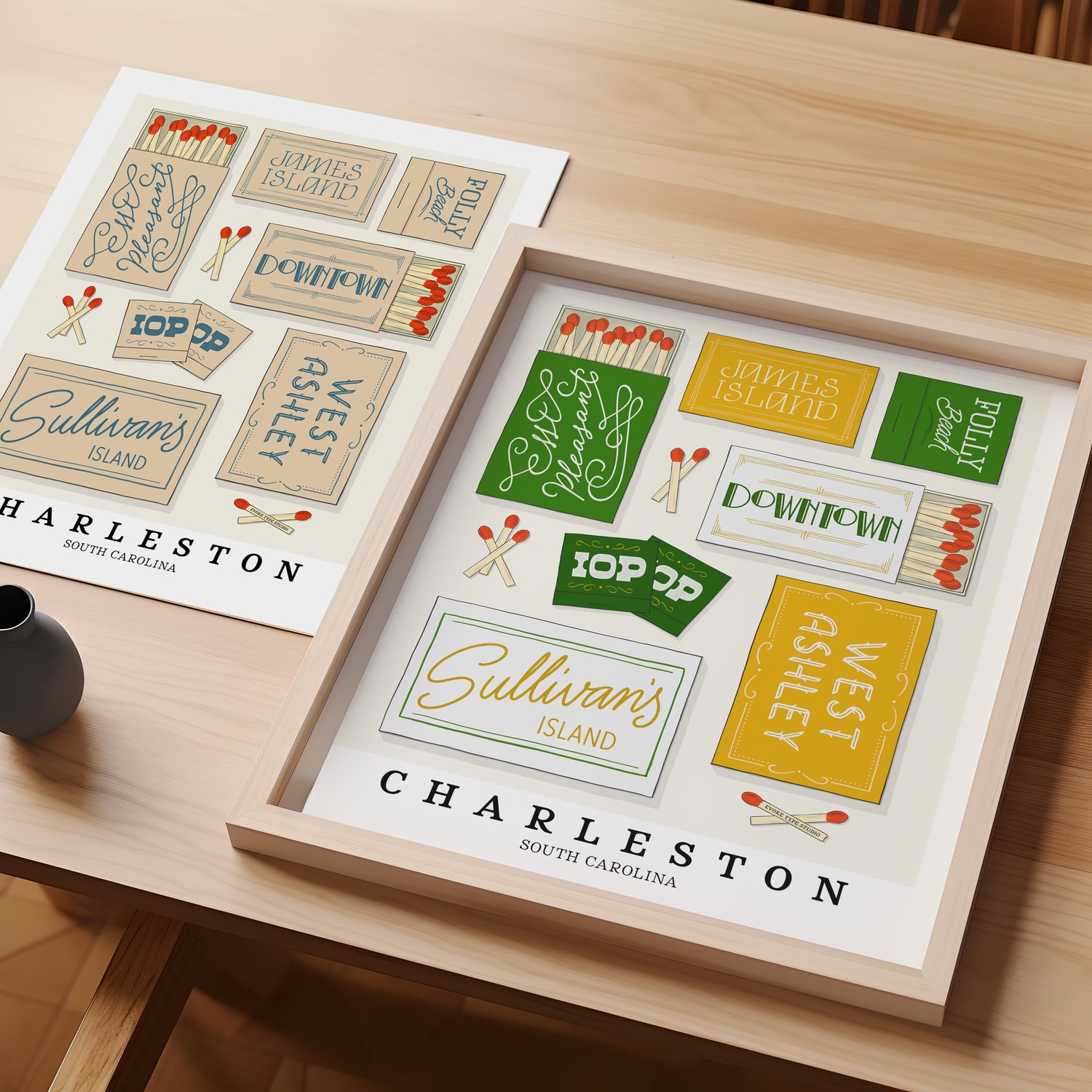 A table with an unframed artwork of Charleston matchbox art and a framed artwork of Charleston matchbox art