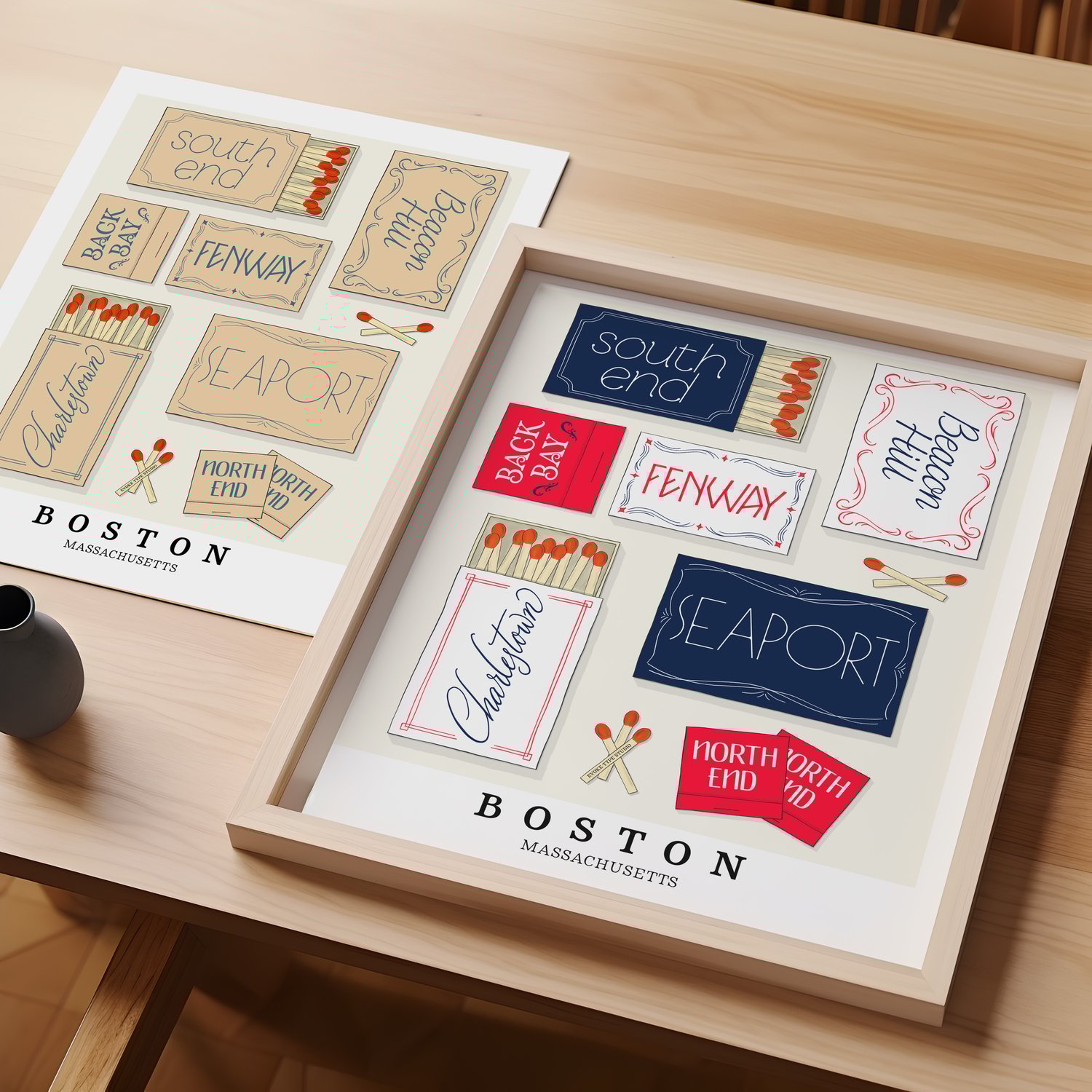 A table with an unframed artwork of Boston matchbox art and a framed artwork of Boston matchbox art