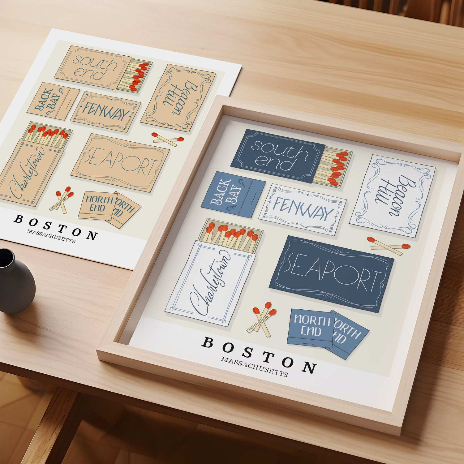 A table with an unframed artwork of Boston matchbox art and a framed artwork of Boston matchbox art