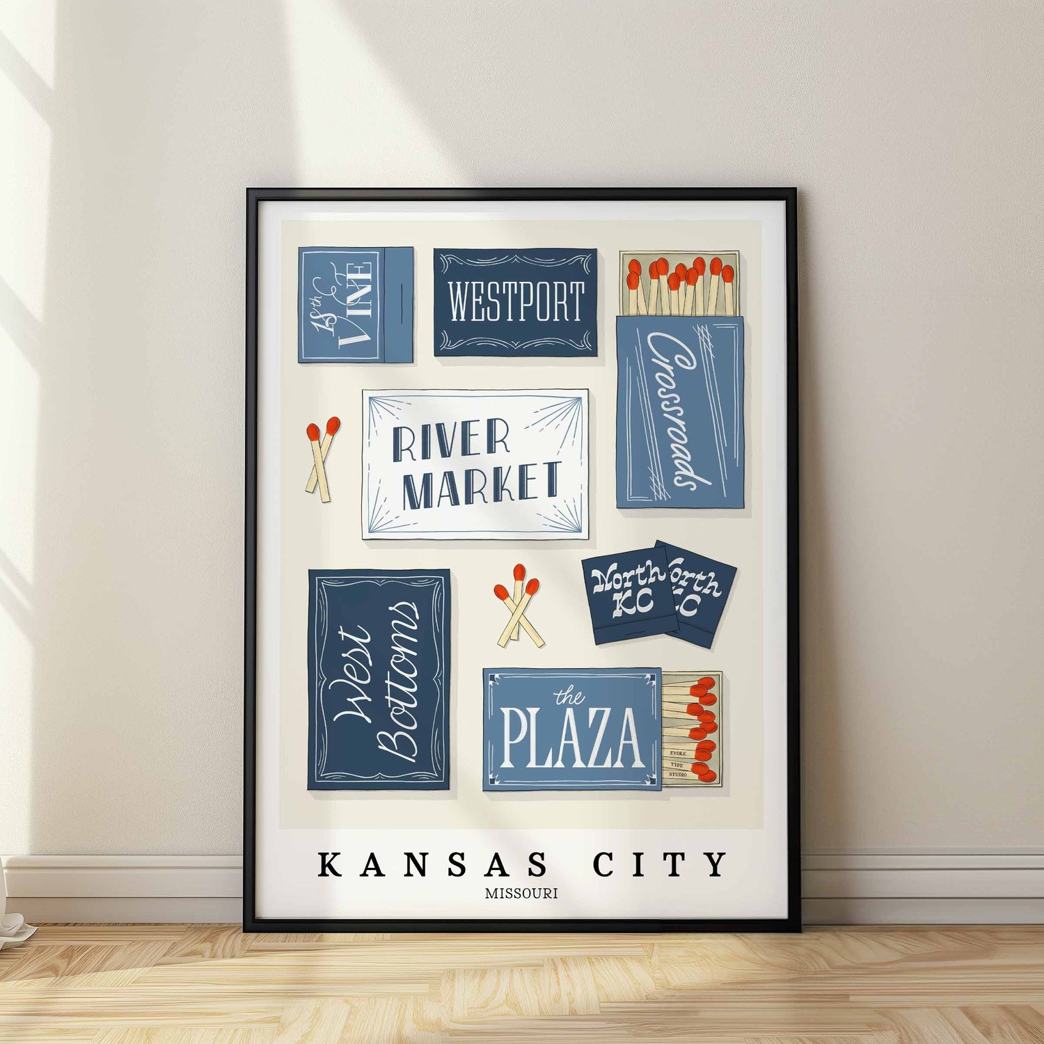 A framed picture of Kansas City, Missouri neighborhoods drawn in various lettering styles on matchboxes. Artwork has a blue and white color scheme