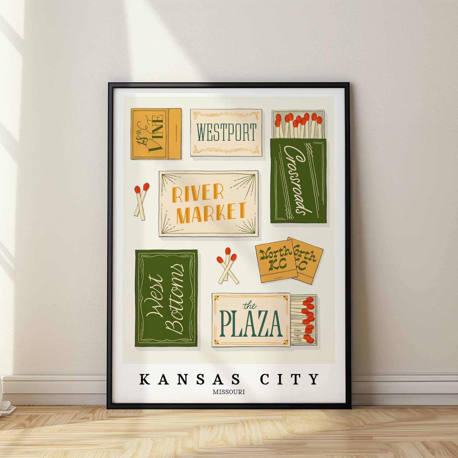 A framed picture of Kansas City, Missouri neighborhoods drawn in various lettering styles on matchboxes. Artwork has a green, yellow, white and blue color scheme