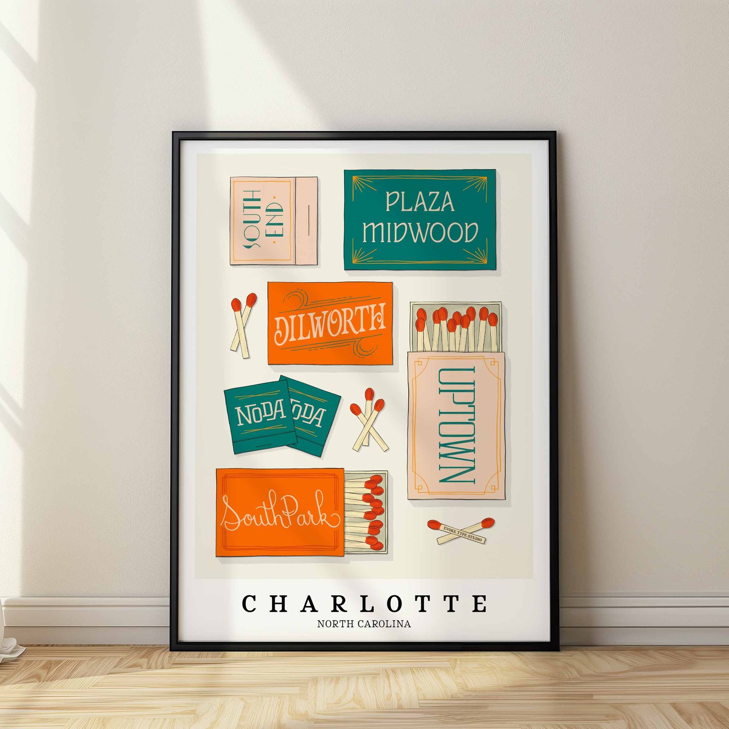 A framed picture of Charlotte, North Carolina neighborhoods drawn in various lettering styles on matchboxes. Artwork has a blue and orange color scheme
