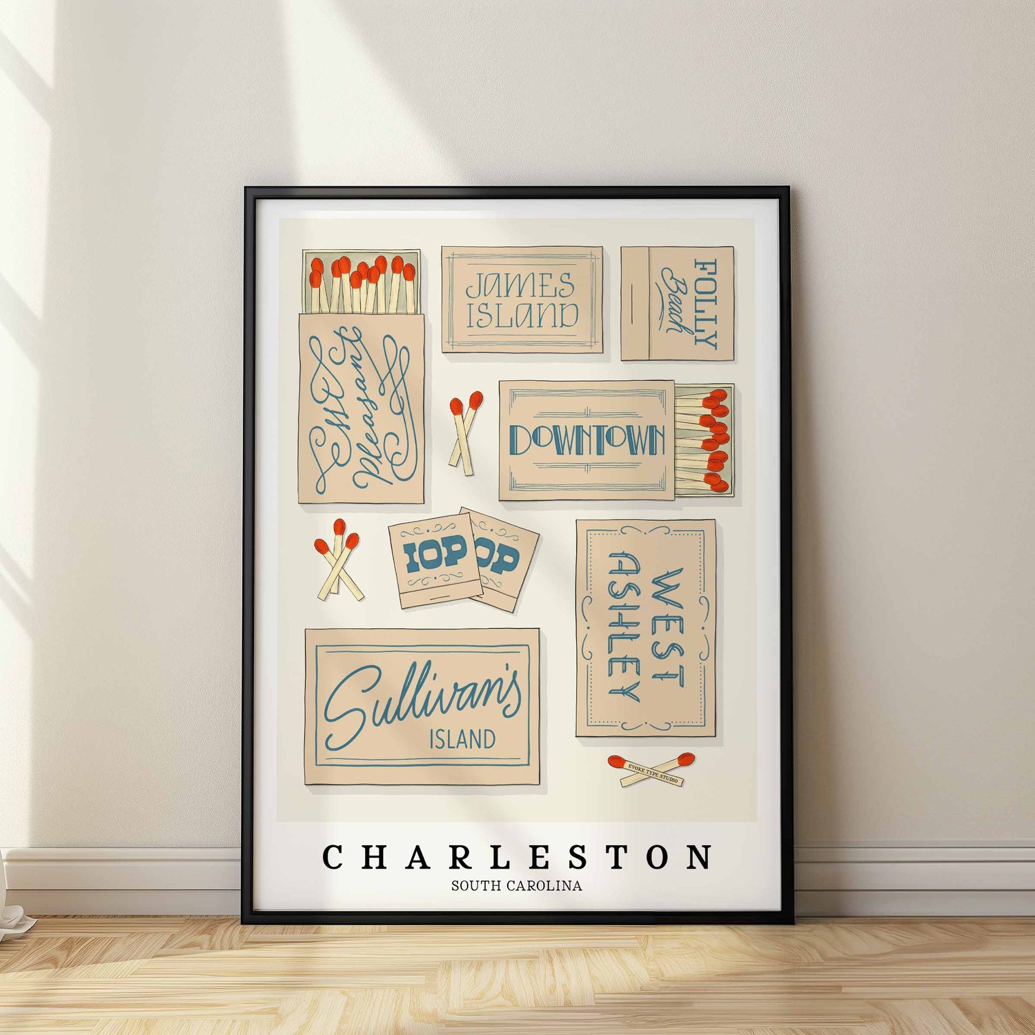 A framed picture of Charleston, South Carolina neighborhoods drawn in various lettering styles on matchboxes. Artwork has a beige and blue color scheme