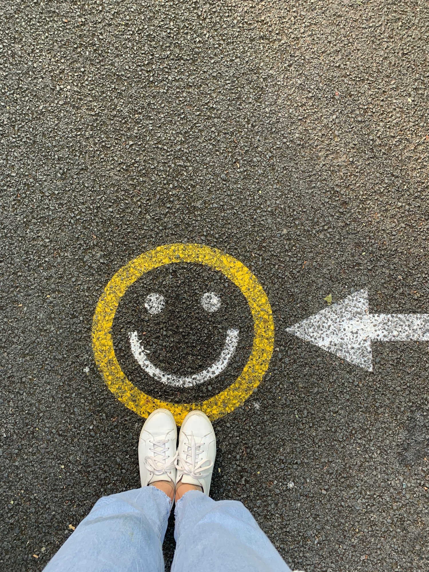 **Alt Text (SEO-Friendly):**   Person standing on pavement with smiley face and arrow pointing right, symbolizing positivity and direction.