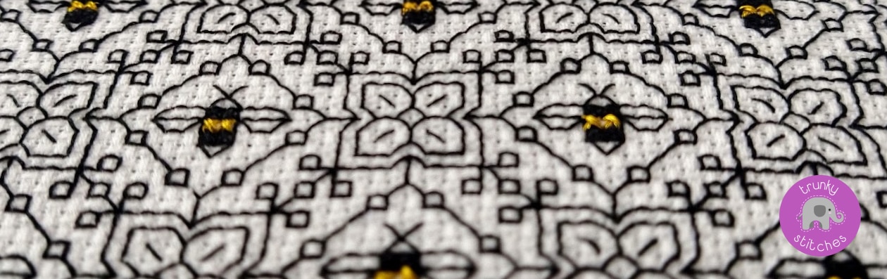 Close up of blackwork embroidery bees stitched in black thread
