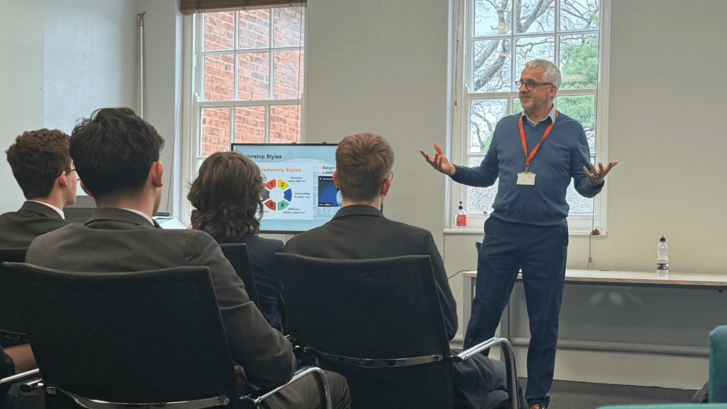 Leadership coach Nick French delivering a presentation on leadership styles to a group of professionals in a meeting room.