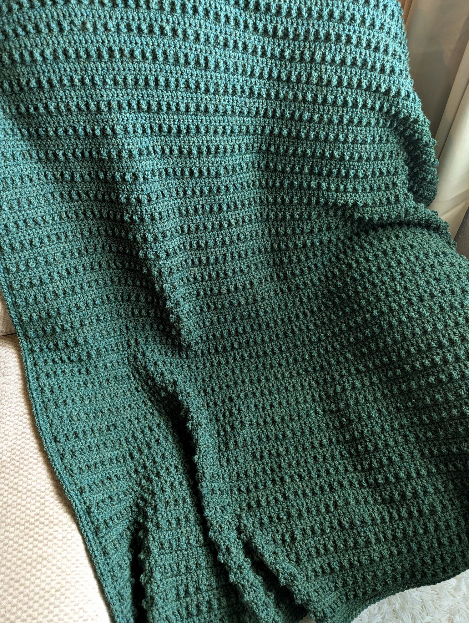 Evergreen crochet blanket pattern on couch