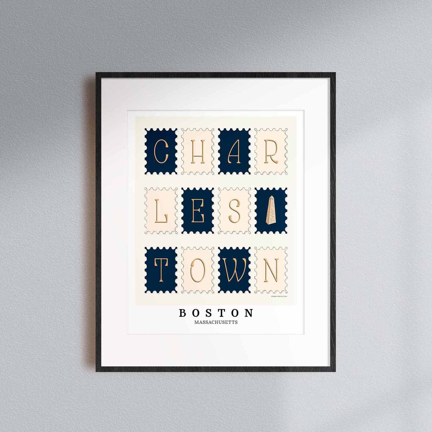 A framed picture of postage stamps featuring the Charlestown neighborhood in Boston, Massachusetts drawn in a unique lettering style. Artwork has a nautical color scheme of navy blue and beige