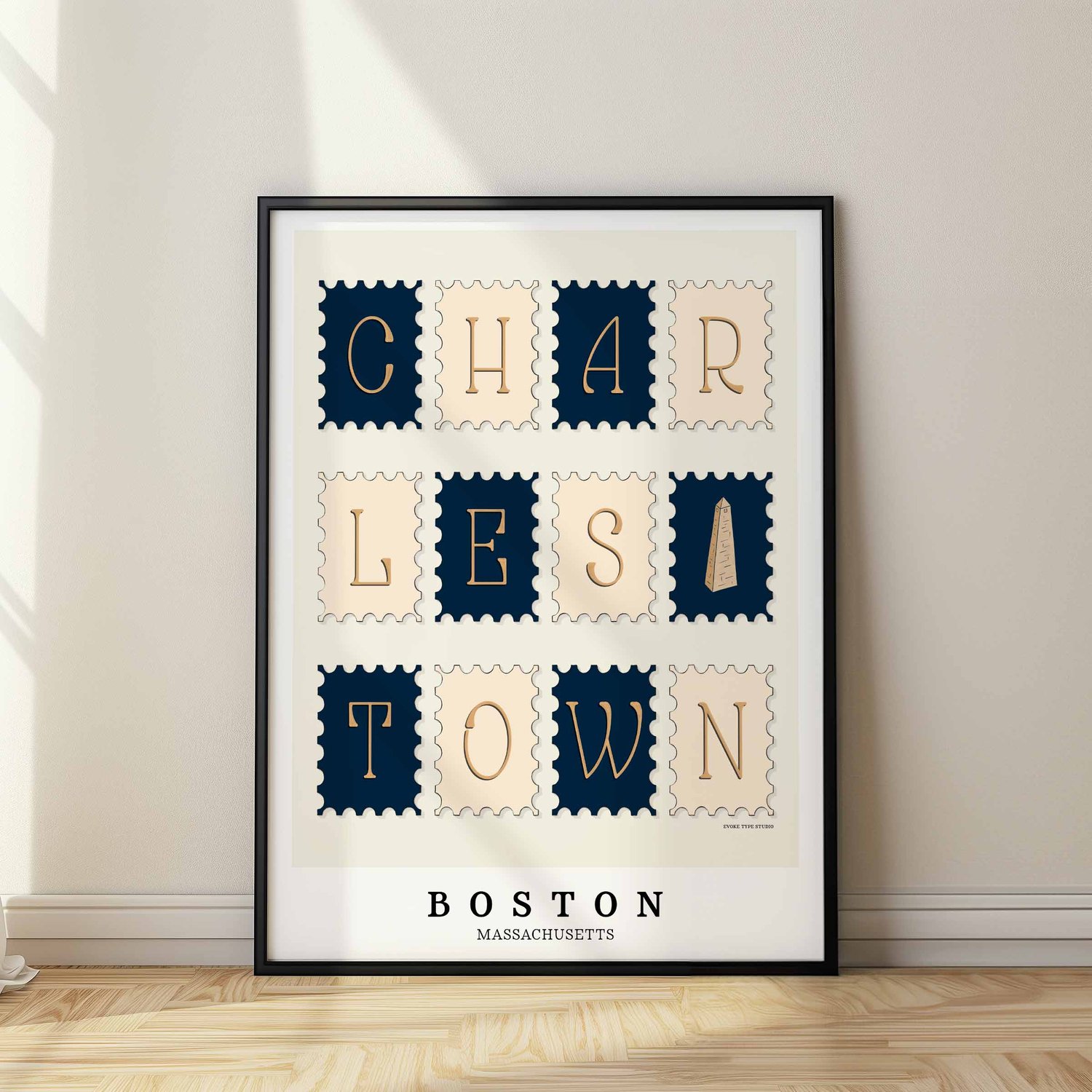 A framed picture of postage stamps featuring the Charlestown neighborhood in Boston, Massachusetts drawn in a unique lettering style. Artwork has a nautical color scheme of navy blue and beige
