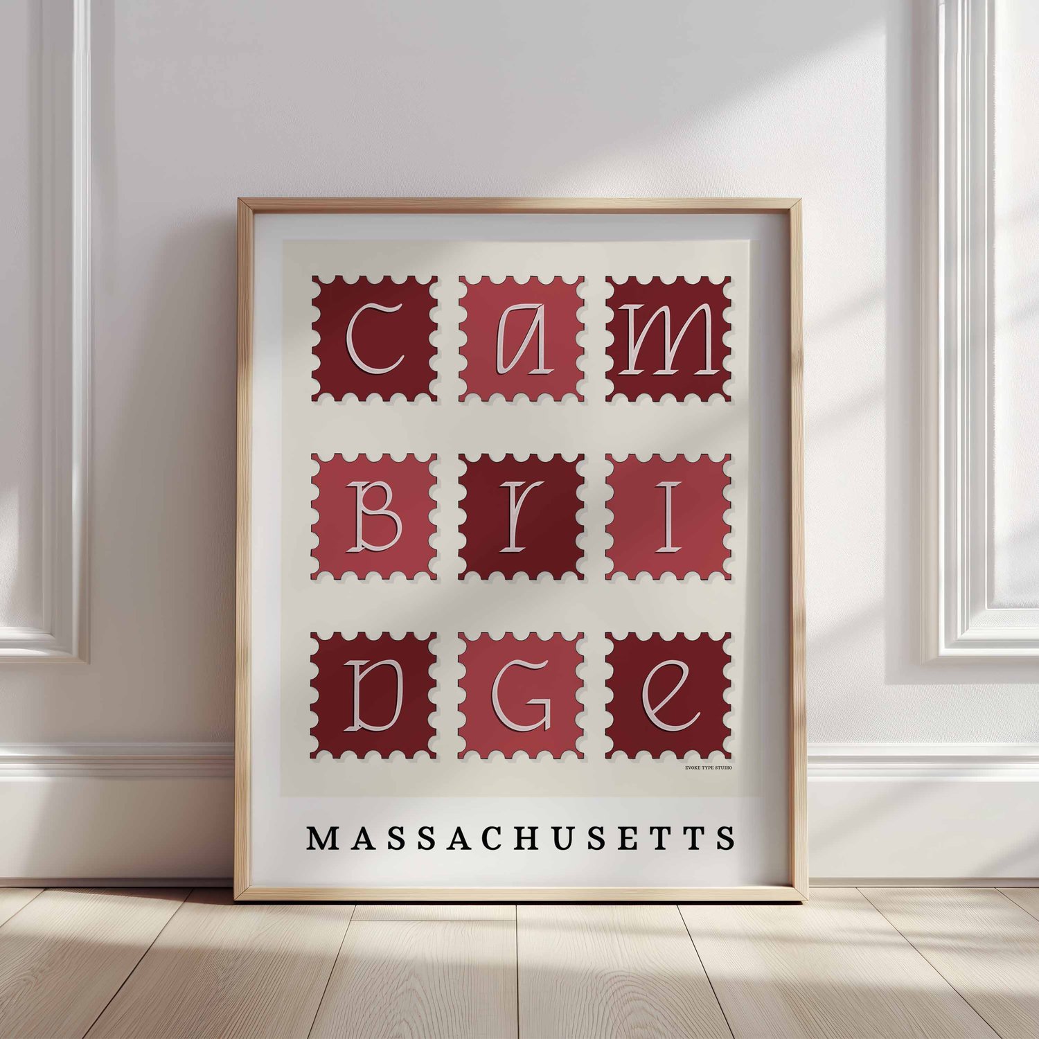 A framed picture of postage stamps featuring Cambridge, Massachusetts drawn in a unique lettering style. Artwork has a red and white color scheme