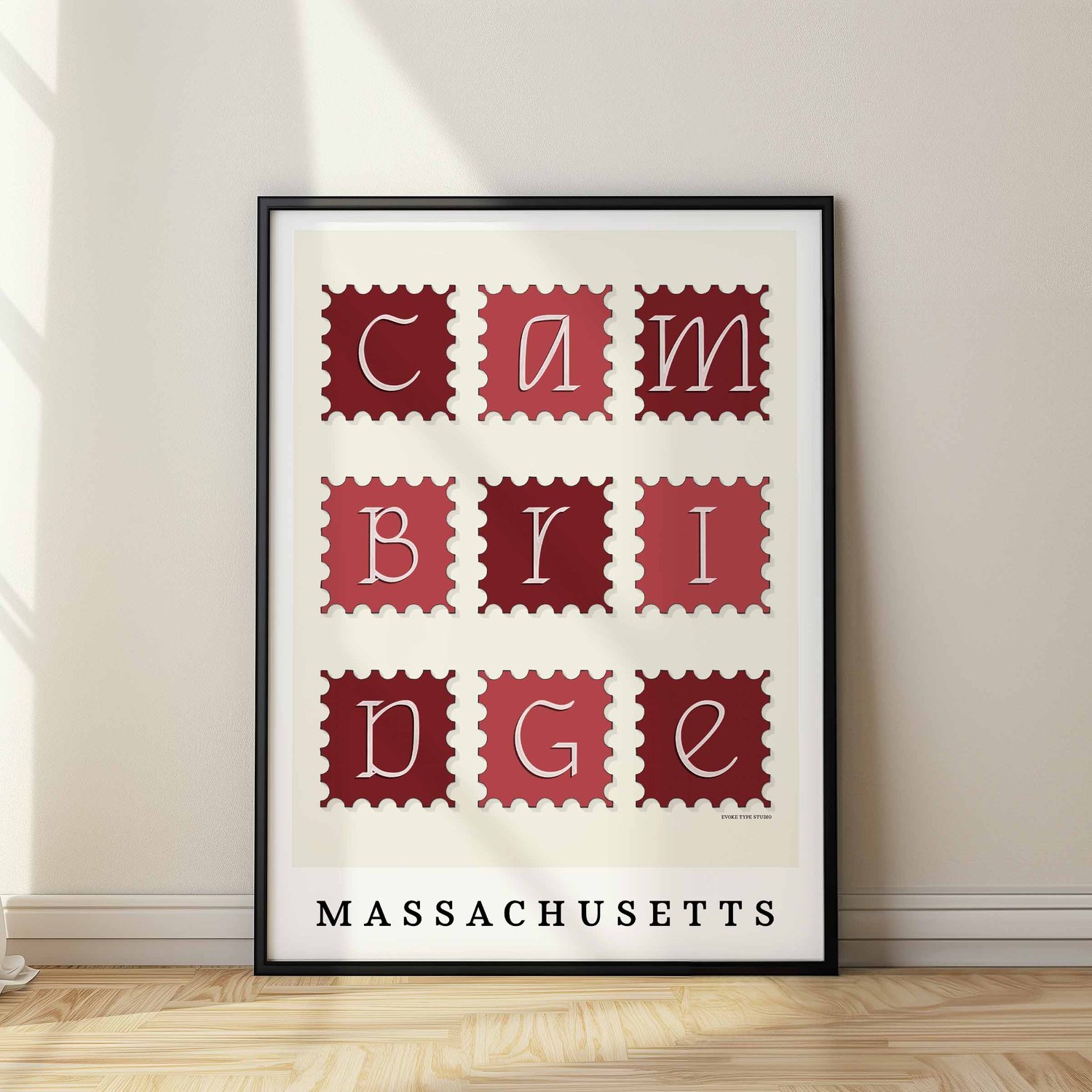 A framed picture of postage stamps featuring Cambridge, Massachusetts drawn in a unique lettering style. Artwork has a red and white color scheme