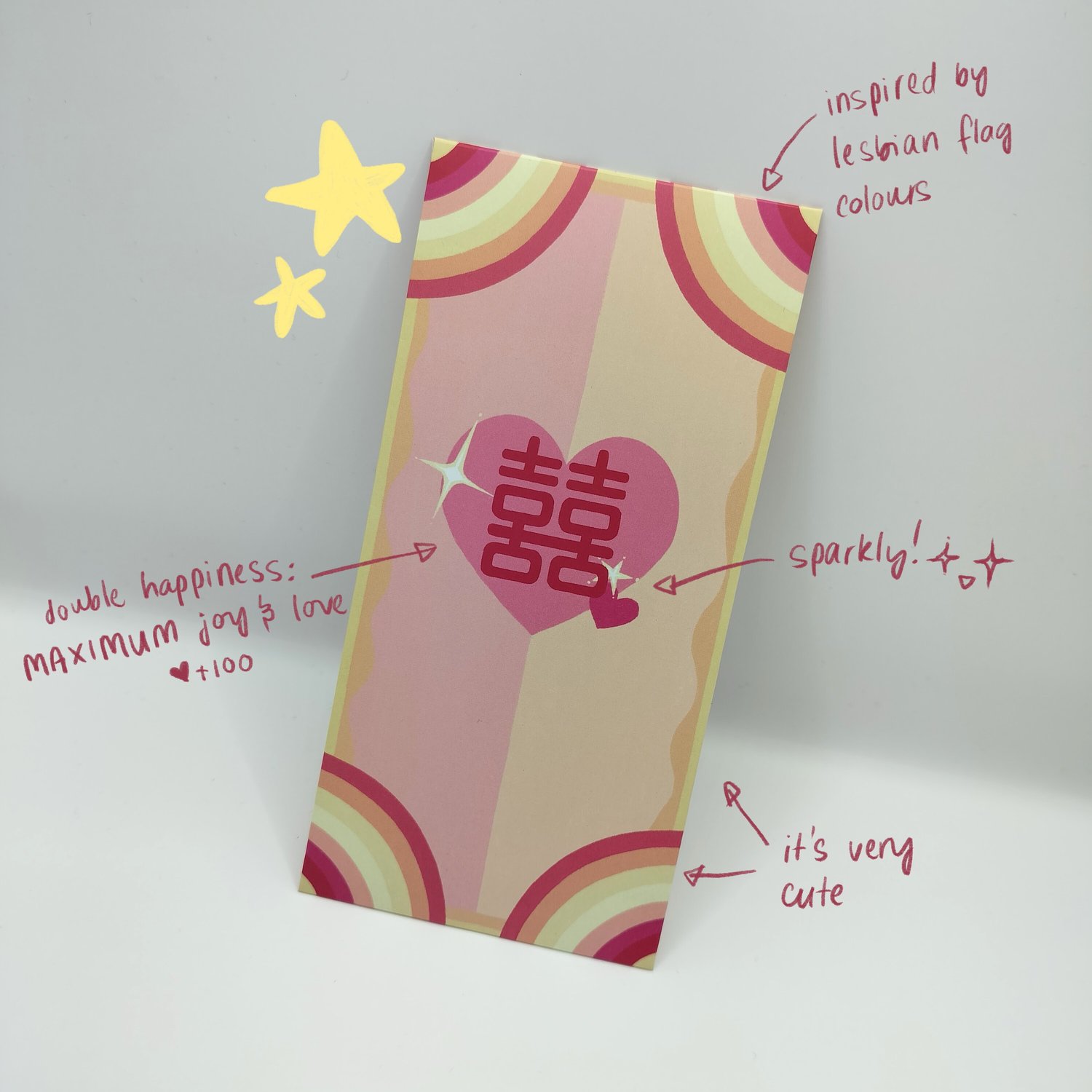 Colorful hongbao in a lesbian flag inspired colour scheme. Has a retro rainbow stripe pattern and a pink heart with Chinese double happiness characters in the center. Labelled with notes pointing out the lesbian flag colours, double happiness, and the cut