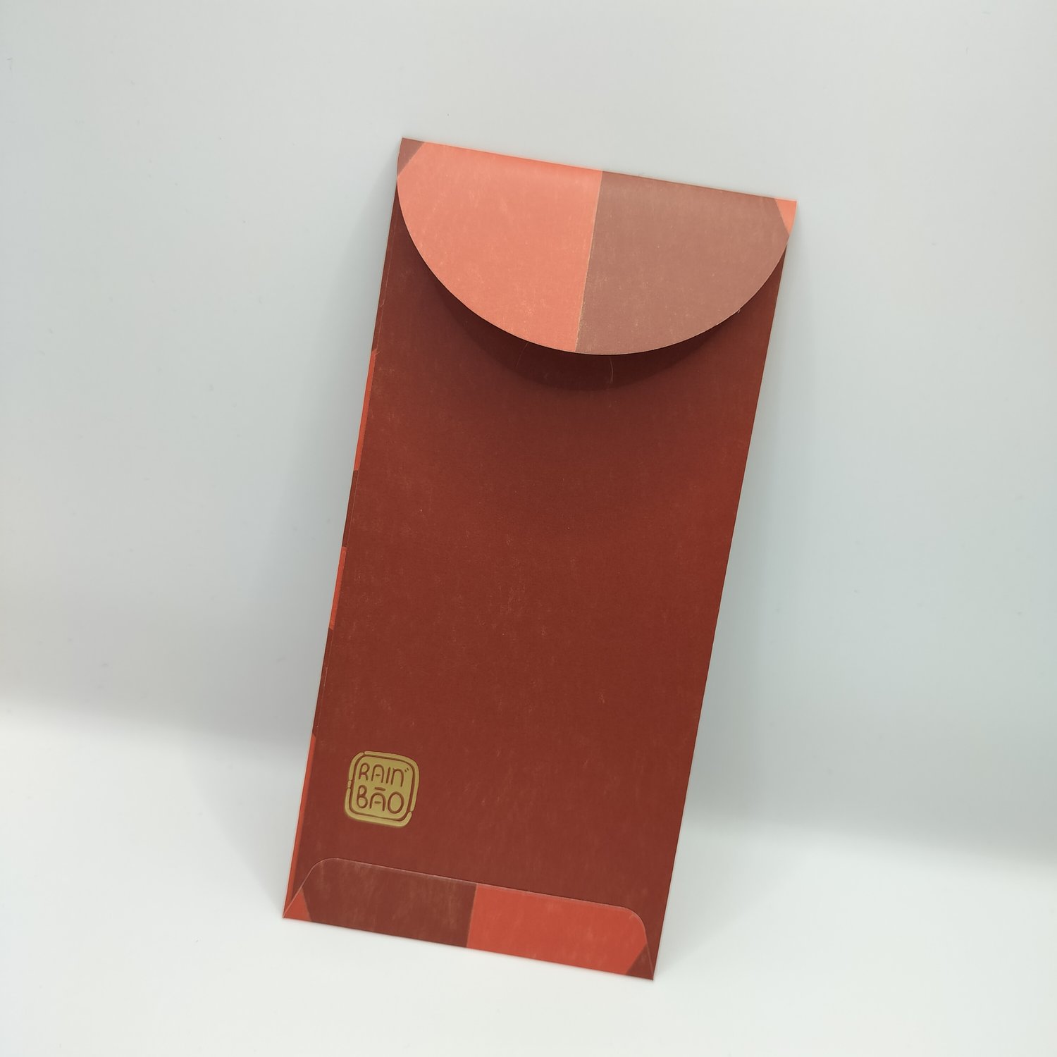 Back of a red envelope with red and dark-red color-blocked design elements and a gold logo stamp in the bottom corner.