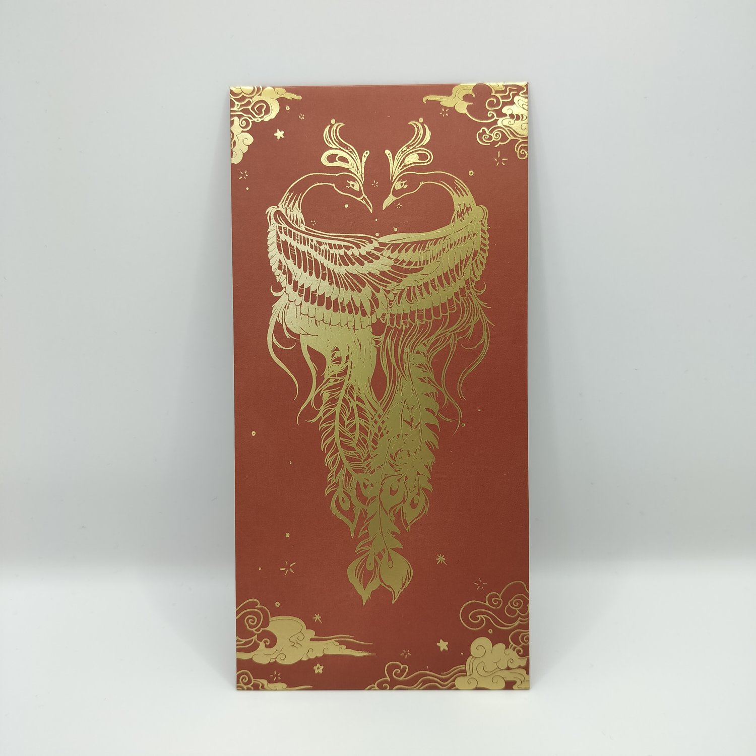 Red money envelope with elaborate gold foil design featuring two phoenixes with detailed feathers, decorative clouds, and ornamental border elements.