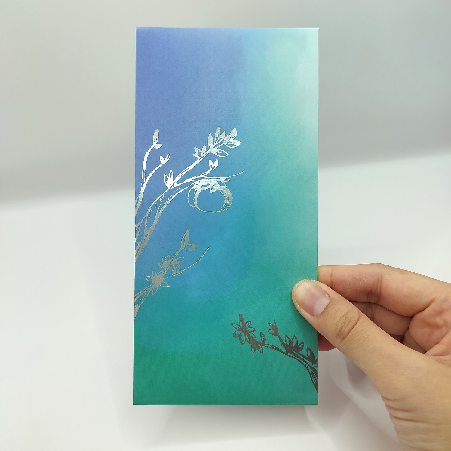 A blue-to-teal gradient envelope with silver botanical foil illustrations.