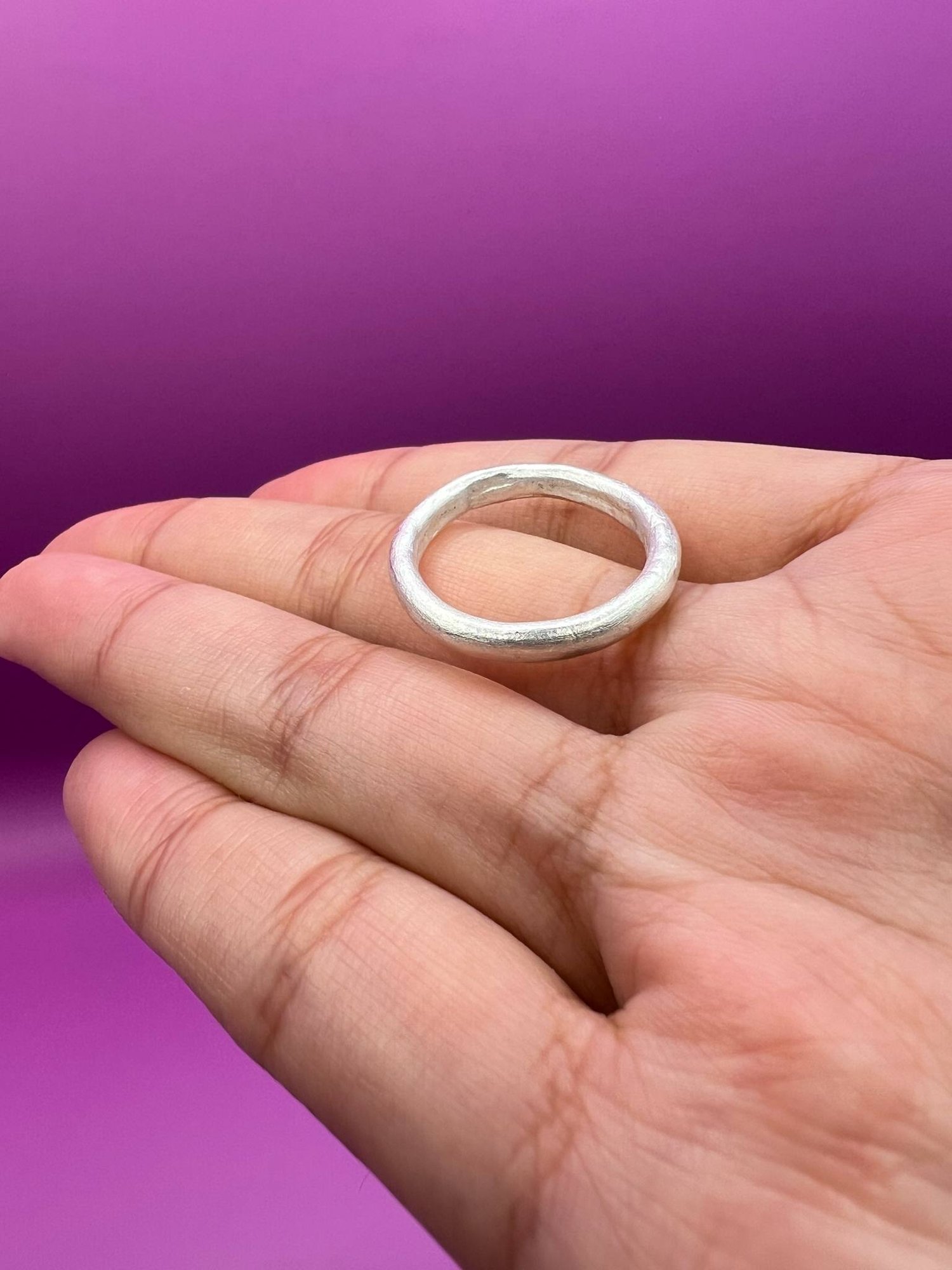 Silver band ring resting on an outstretched hand.