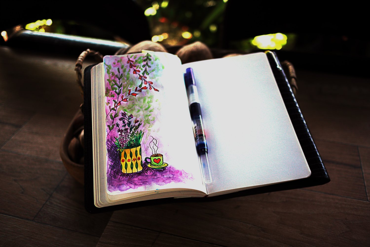 An open notebook journal with a garden painting on the left page and a blank page on the right