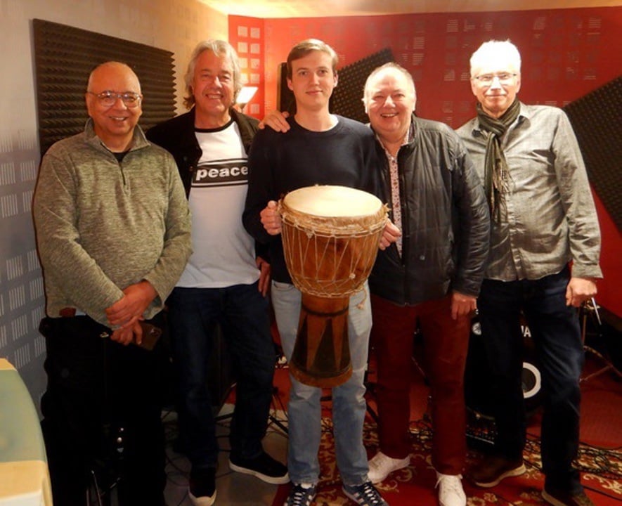 group of the team of walk with me posing for photograph with a djembe in the middle after recording more than friends the b side for walk with me single by dave wells, raising money for parkinsons uk