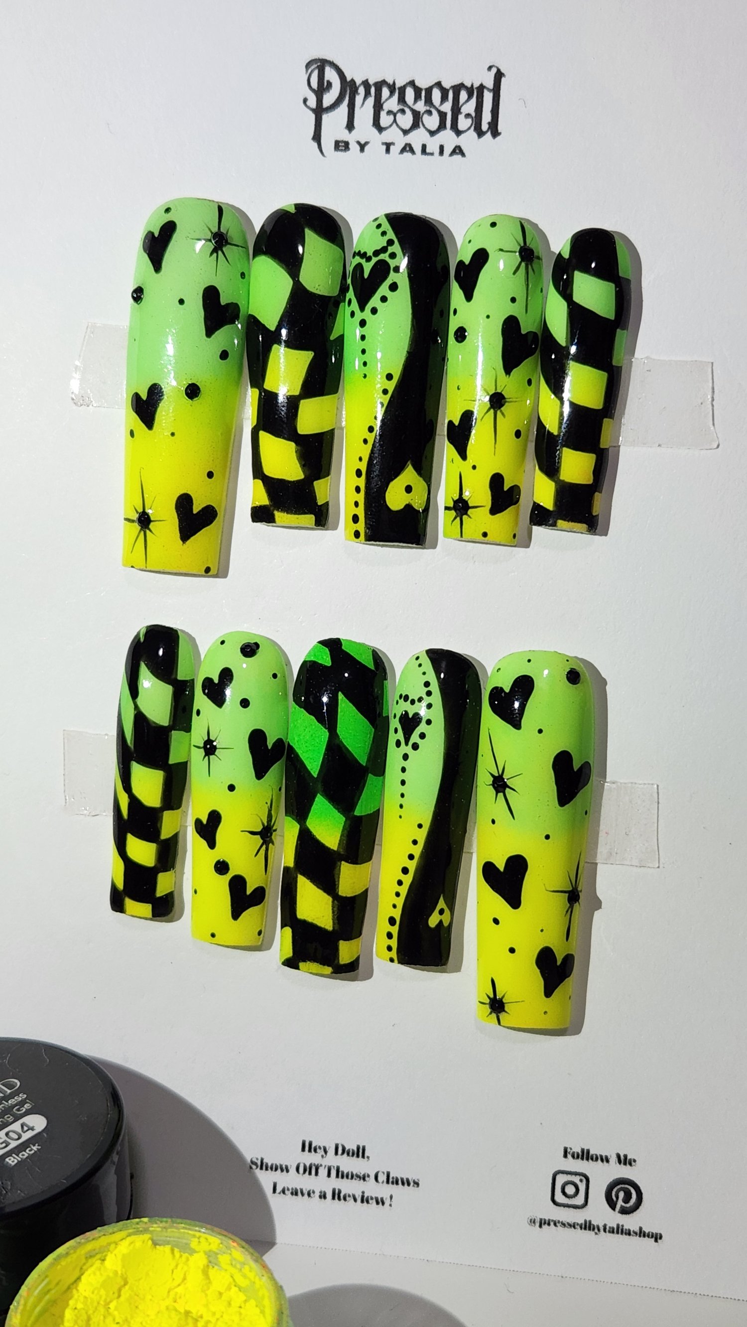 Long square shaped press-on nails with lemon yellow and lime green neon pigment powder ombre, hand painted checkered print designs in black gel polish, yin and yang heart designs in black, and hearts and stars designs in black, add black rhinestones, clos