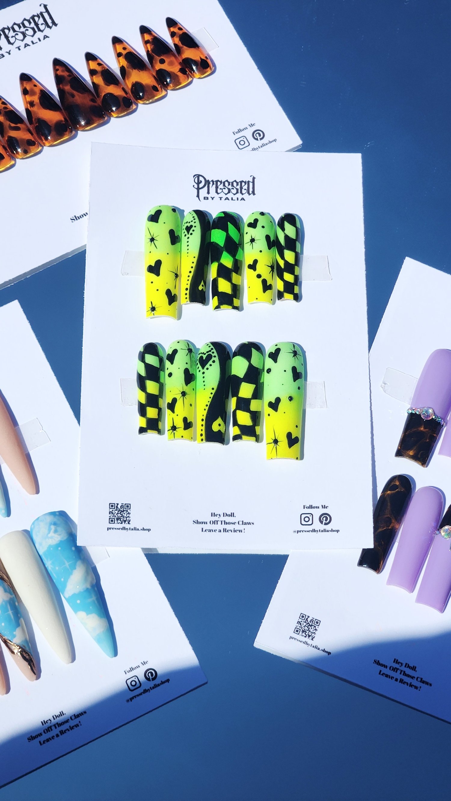 Long square shaped press-on nails with lemon yellow and lime green neon pigment powder ombre, hand painted checkered print designs in black gel polish, yin and yang heart designs in black, and hearts and stars designs in black, add black rhinestones, surr