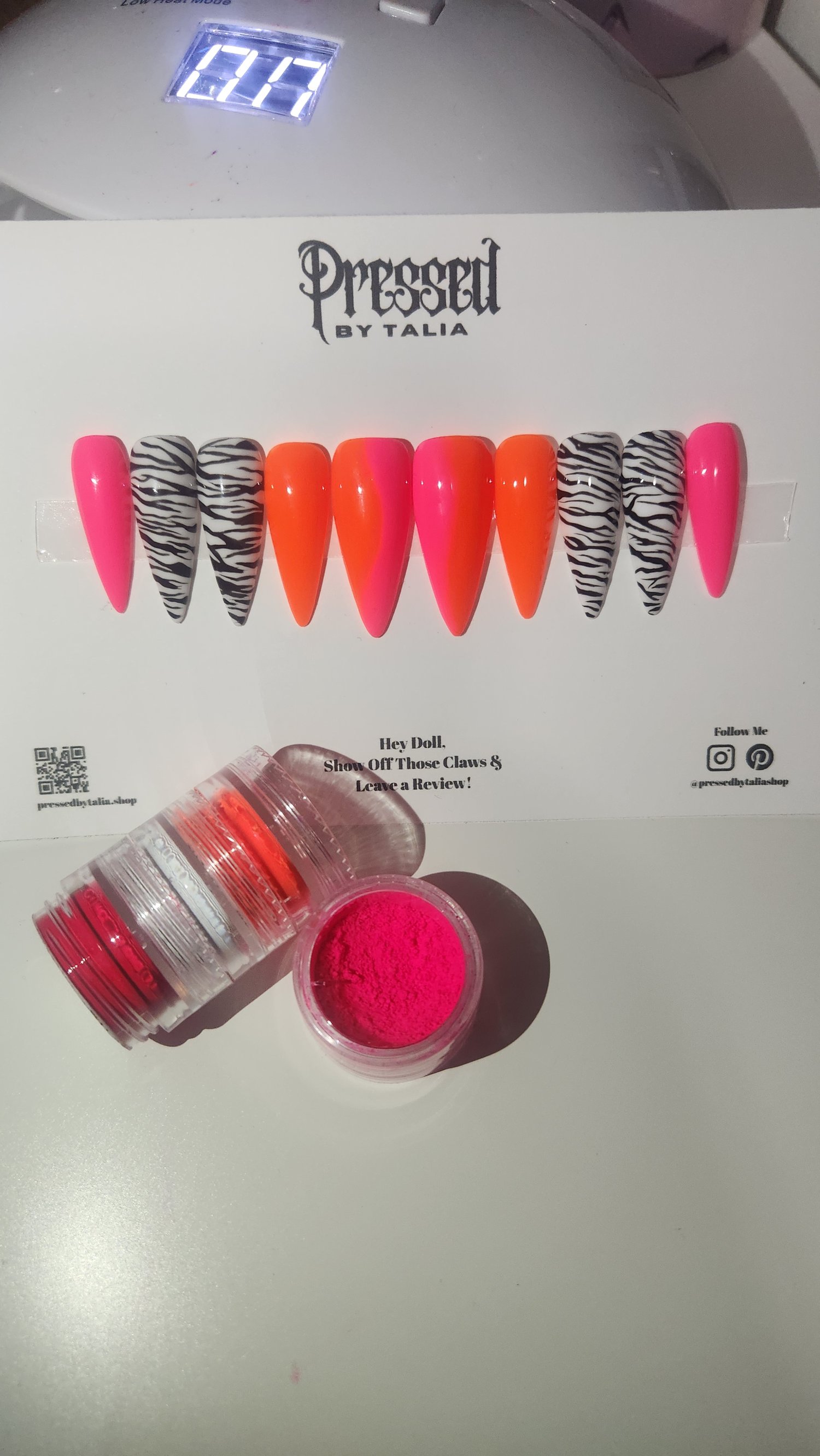 Medium length stiletto shaped press-on nails with hot pink and neon orange ombre and handmade zebra printed designs nails, close-up picture on Pressed By Talia branded card