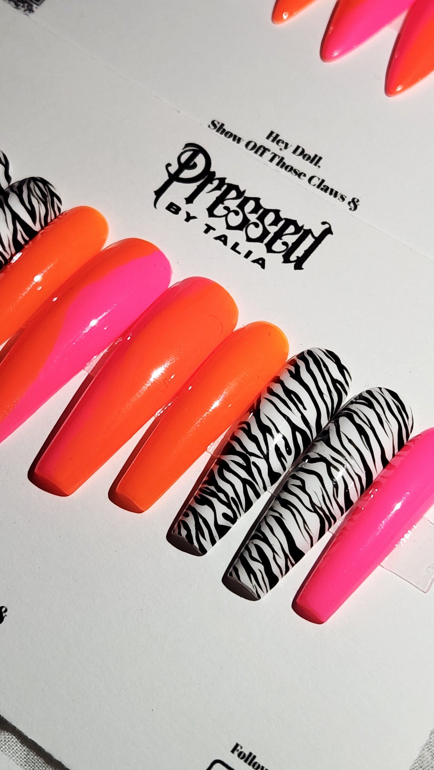 Extra long coffin shaped press-on nails with hot pink and neon orange ombre and handmade zebra printed nails, close-up picture on Pressed By Talia branded card