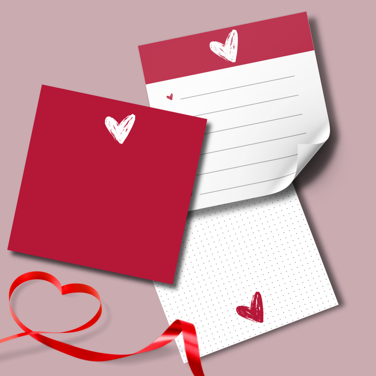 “Close-up of three printable memo pads with dot, grid, and blank styles, featuring red heart sketches and curled page edges on a soft pink background.”