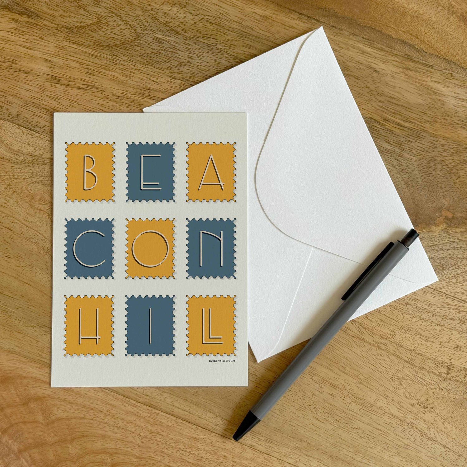A colorful notecard sitting on a table with a white envelope and pen.