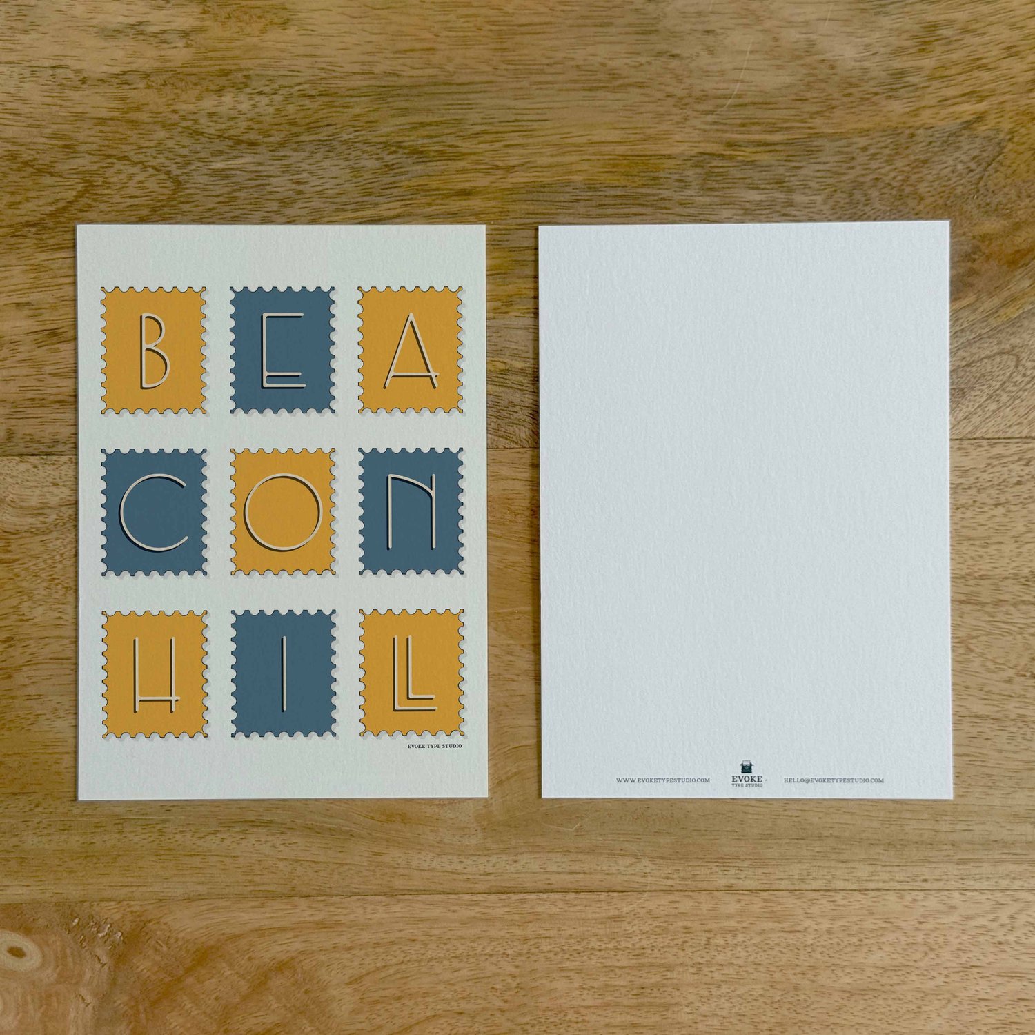 Two sides of a notecard, with postage stamp artwork on the front and a mostly blank back with company contact information at the bottom of the notecard.