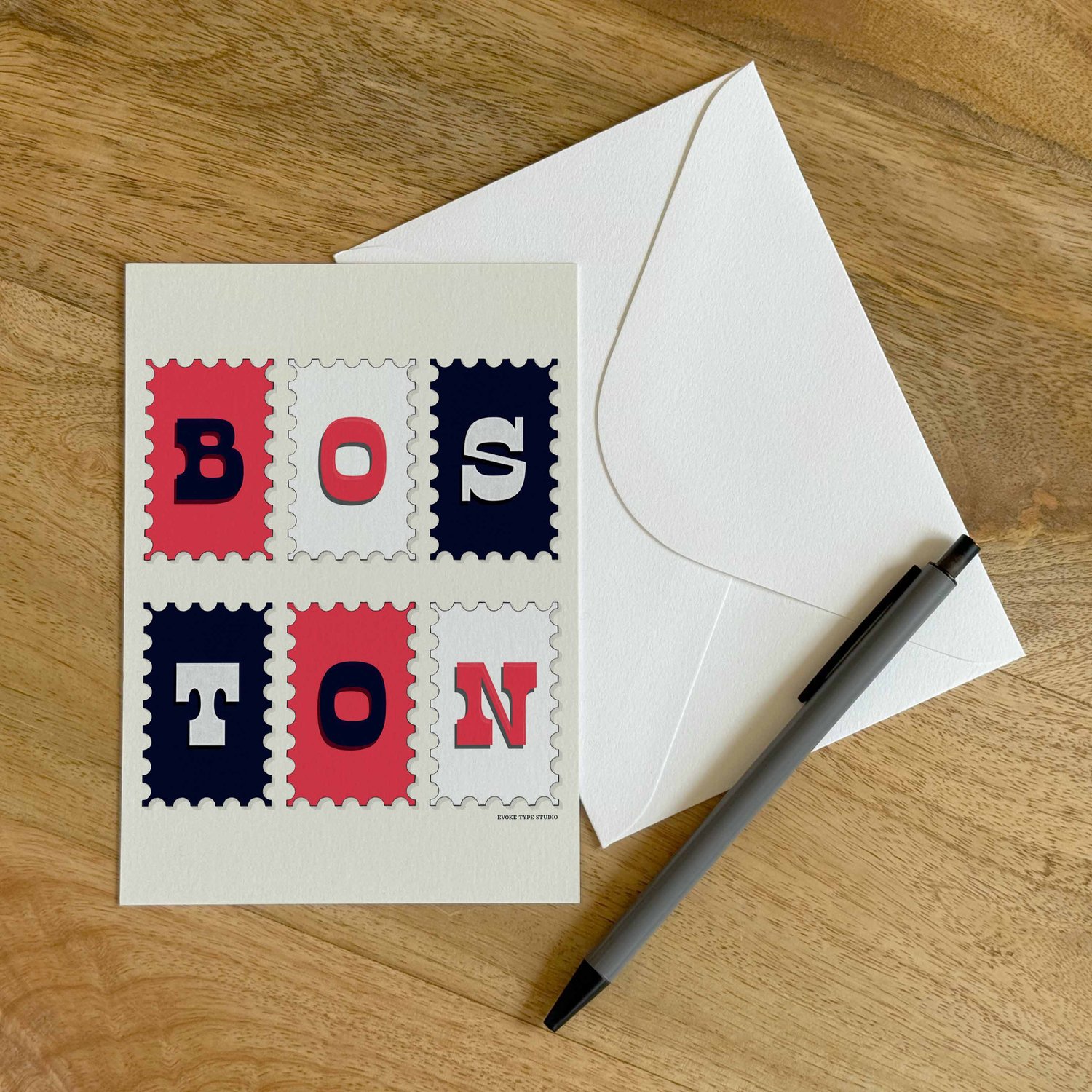 A colorful notecard sitting on a table with a white envelope and pen.