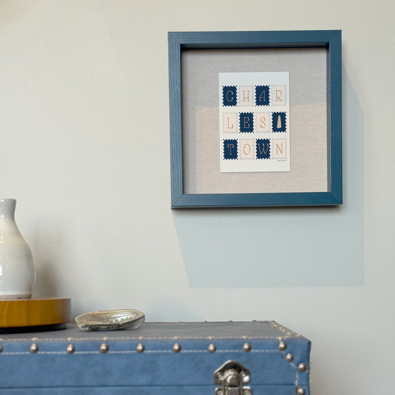 A framed notecard in a shadow box hung on the wall with decorative items placed nearby.