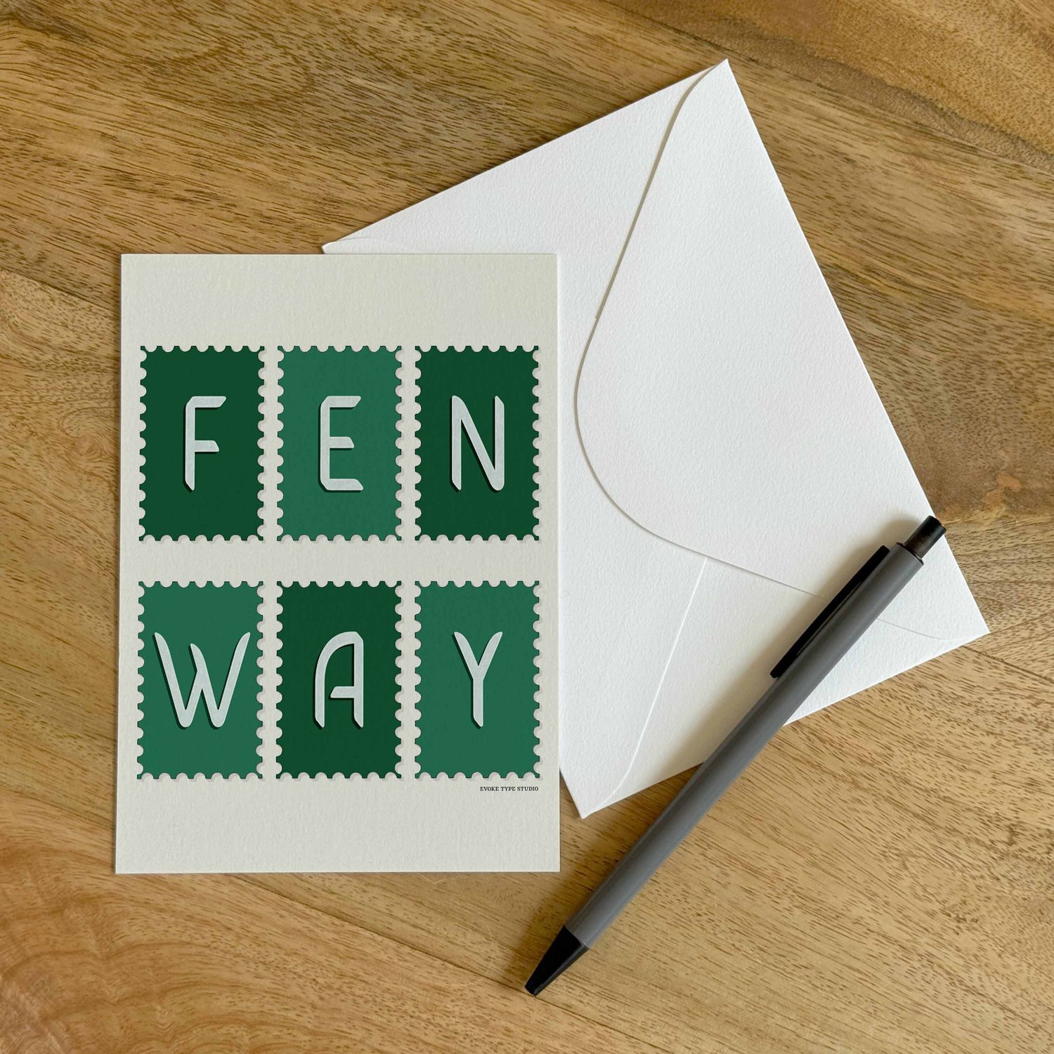 A colorful notecard sitting on a table with a white envelope and pen.