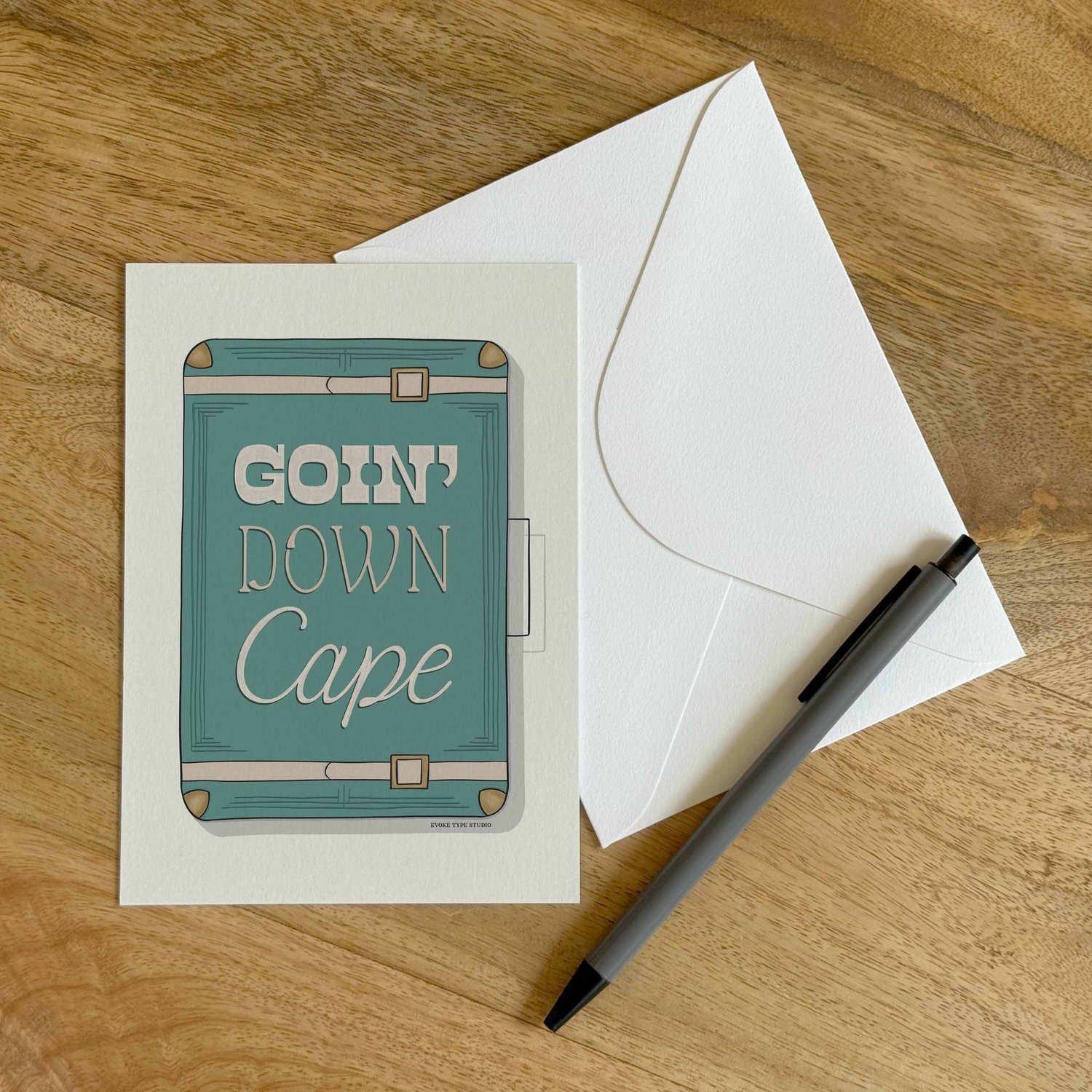 A colorful notecard sitting on a table with a white envelope and pen.