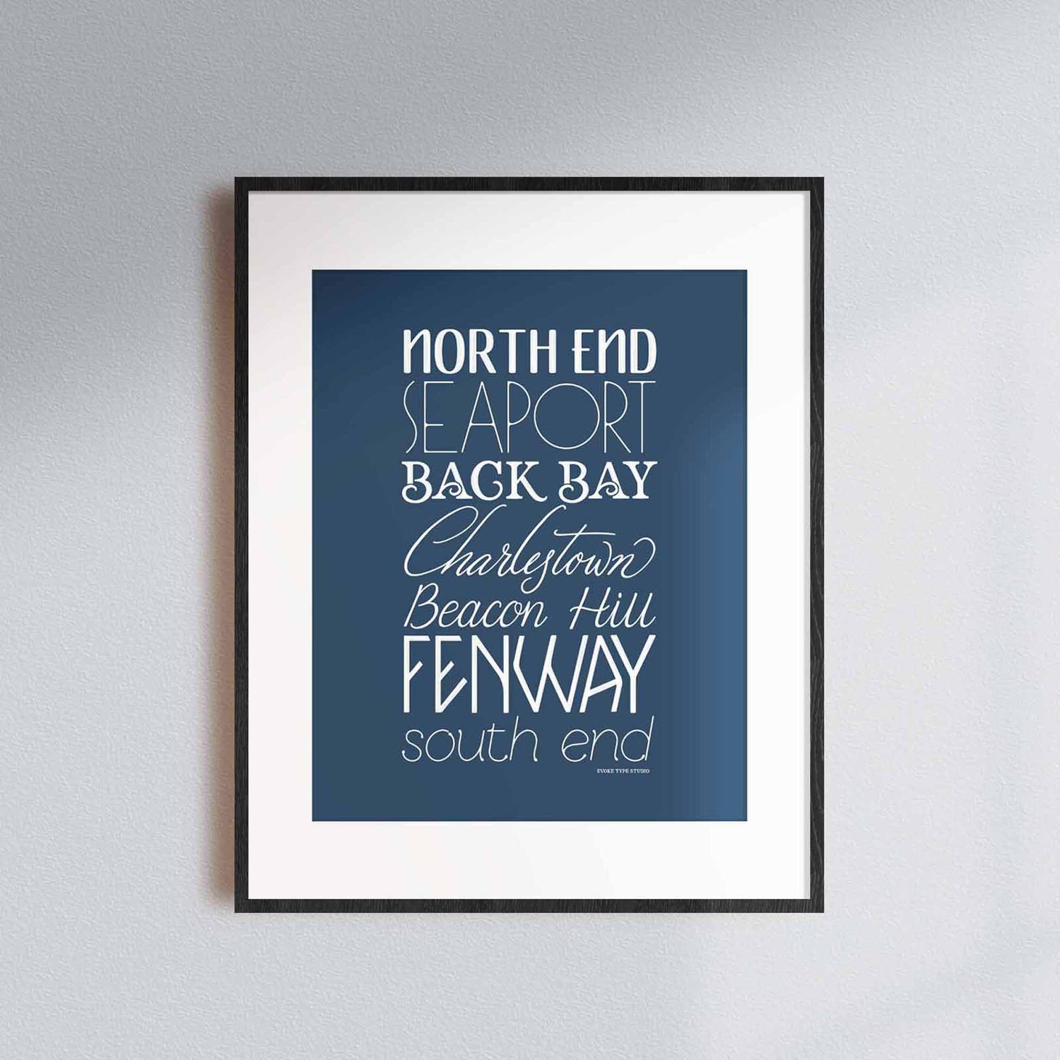 A framed picture of Boston, Massachusetts neighborhoods drawn in various lettering styles. Artwork has a blue and white color scheme