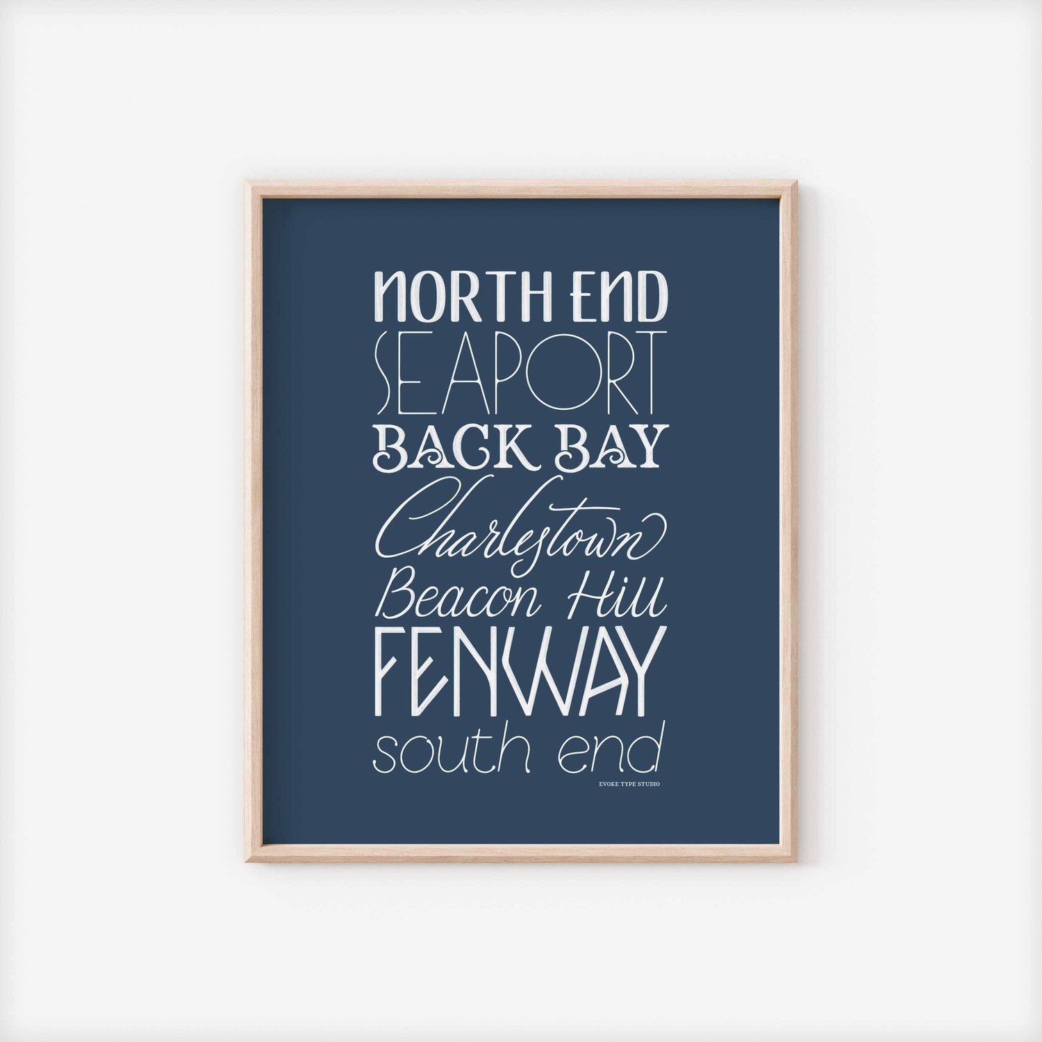 A framed picture of Boston, Massachusetts neighborhoods drawn in various lettering styles. Artwork has a blue and white color scheme