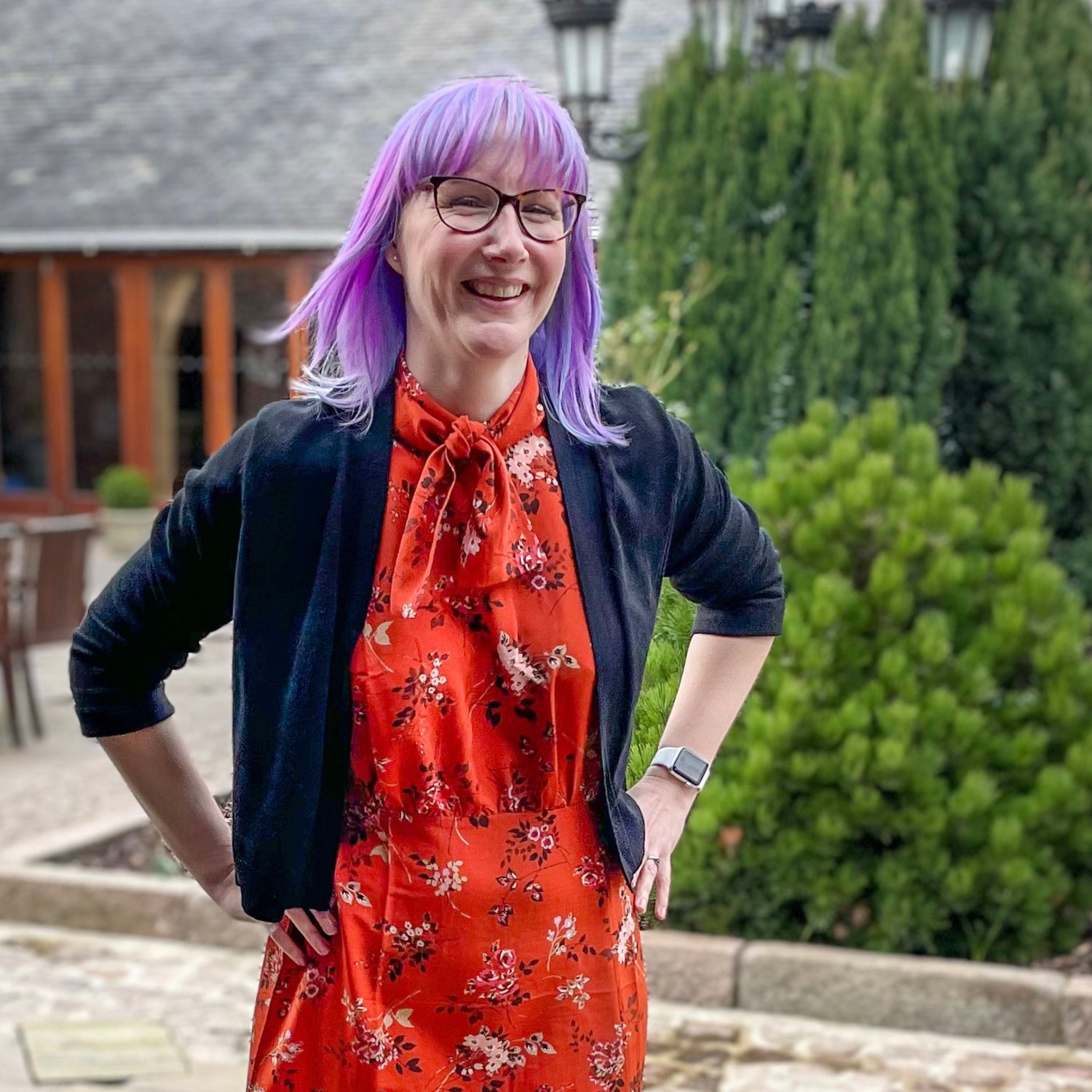 A portrait of Emma in an orange dress and black cardigan.