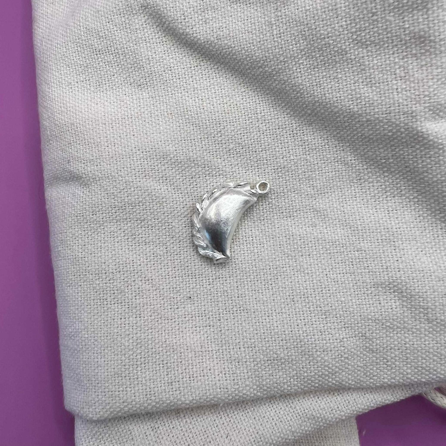 Silver curry puff pendant on off-white fabric