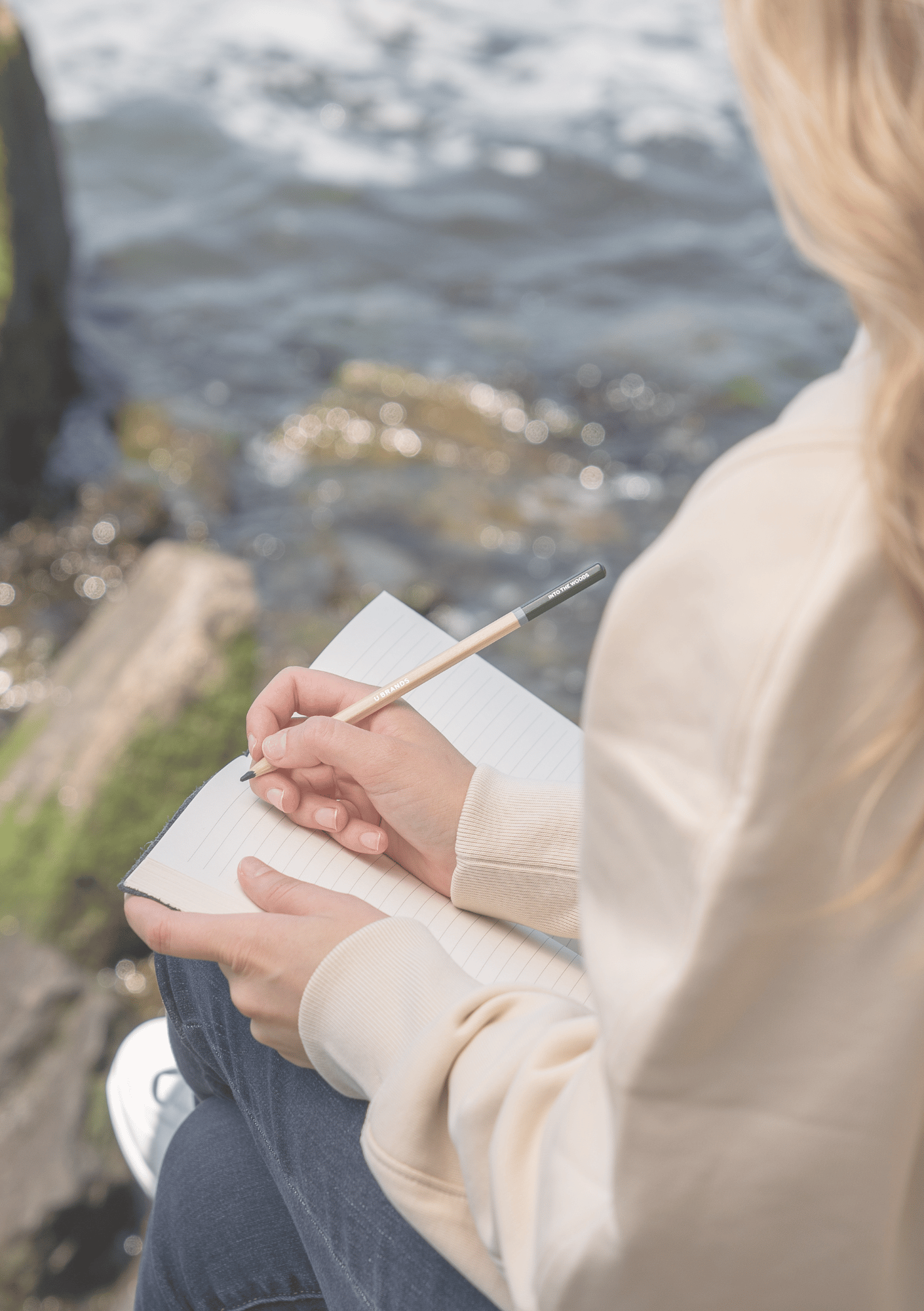 Woman sitting by water writing in a notebook, symbolizing reflection, clarity, and personal growth — image for Intuitive Guidance page on iamisabelbar.com
