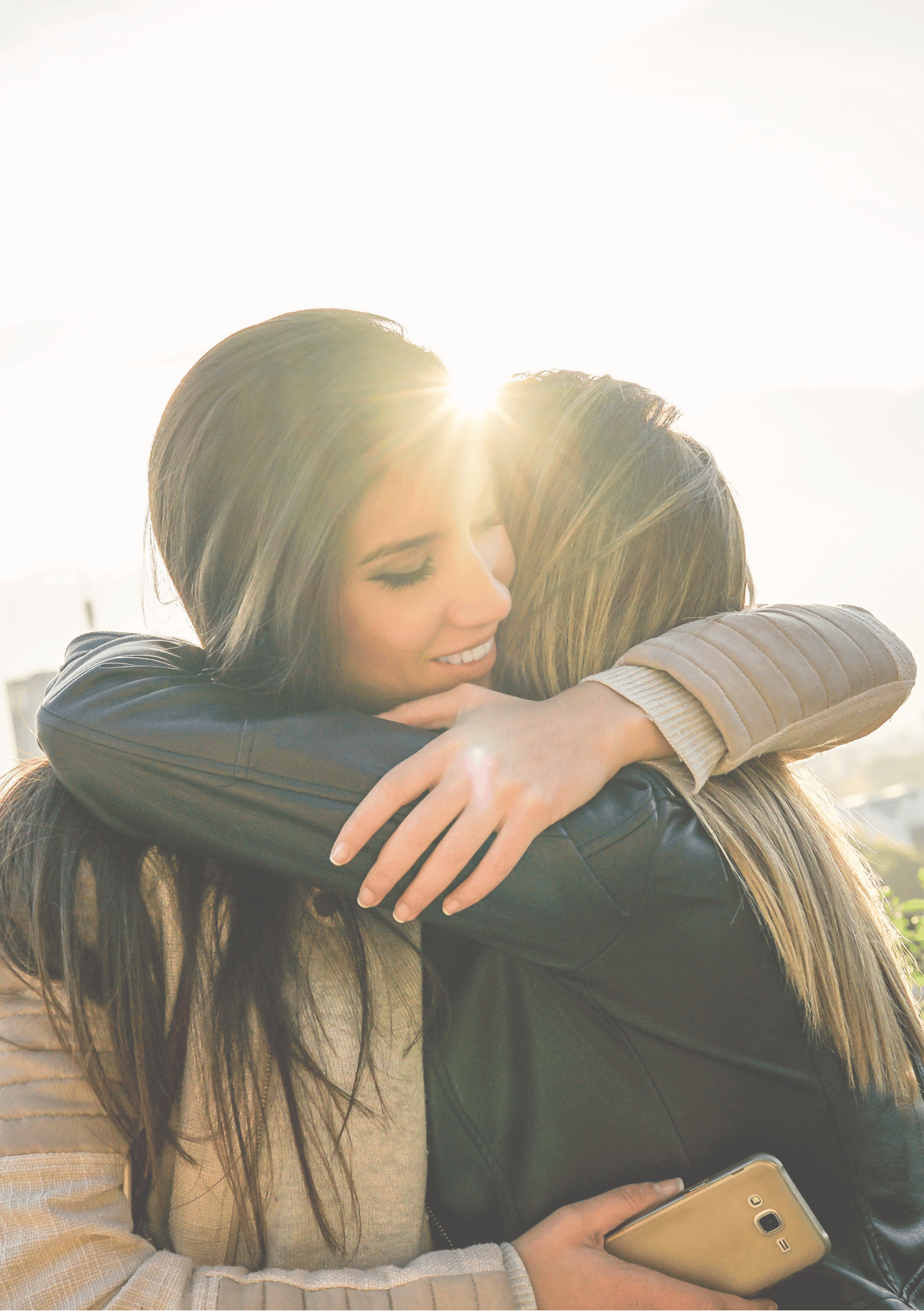 Two women embracing warmly outdoors with sunlight glowing behind them, symbolizing connection, support, and healing — image for Intuitive Soul Guidance Voxer page on iamisabelbar.com