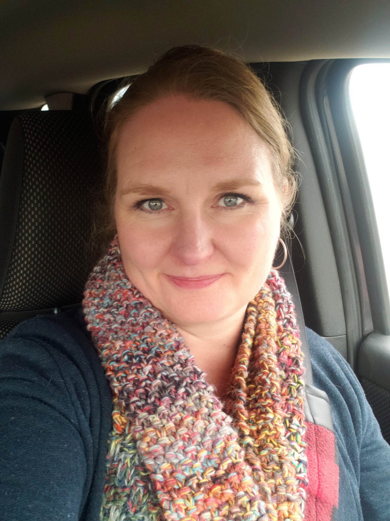 Talena wearing a Stash Potion Cowl, sitting in her car, and smiling at the camera.
