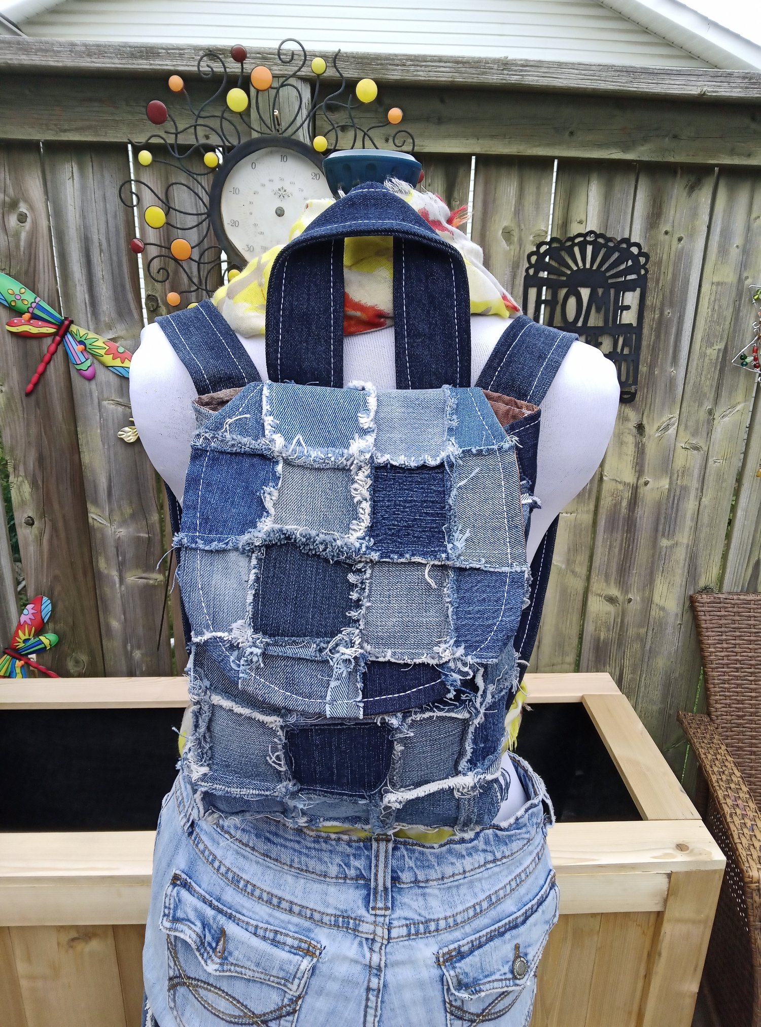 Handmade upcycled denim backpack bag crafted from recycled blue jeans with raw frayed edges, patchwork detailing, and boho festival-inspired styling. This sustainable patchwork purse features textured denim layers, artistic stitching, and unique handmade character.  Frayed Spirit – Wanderthread Edition blends sustainable fashion, handmade craftsmanship, and free-spirited festival style into a one-of-a-kind wearable art bag.