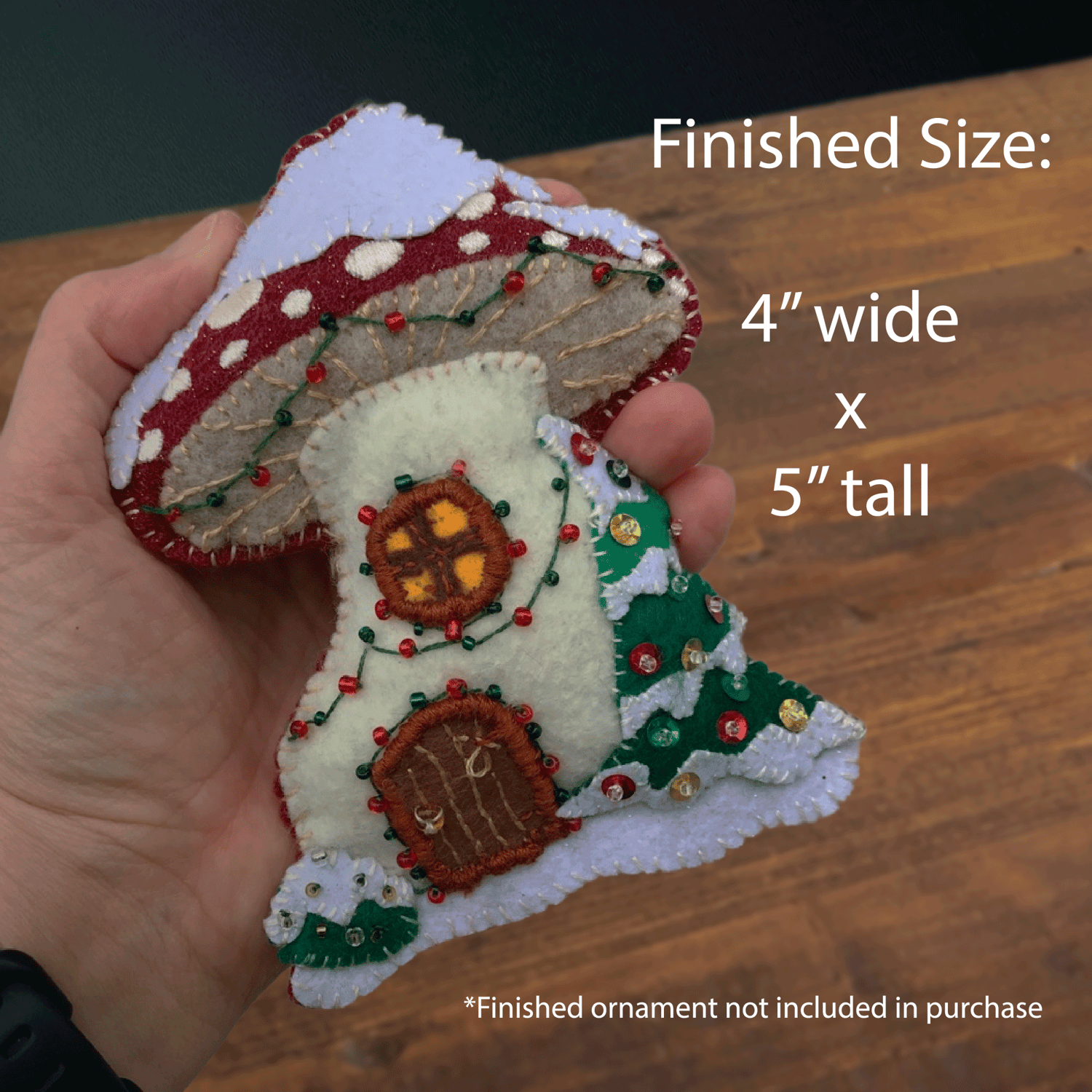 The ornament held in hand to show the finished size of 4" wide by 5" tall.
