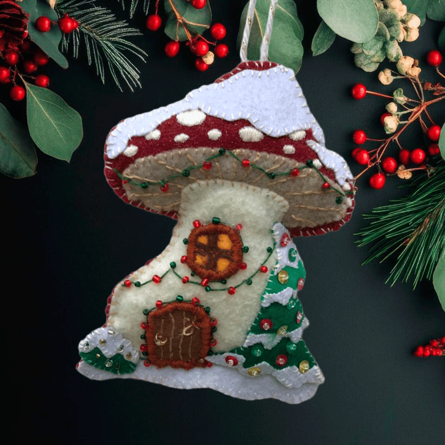 A felt ornament in the shape of a fairy house made from a mushroom.
