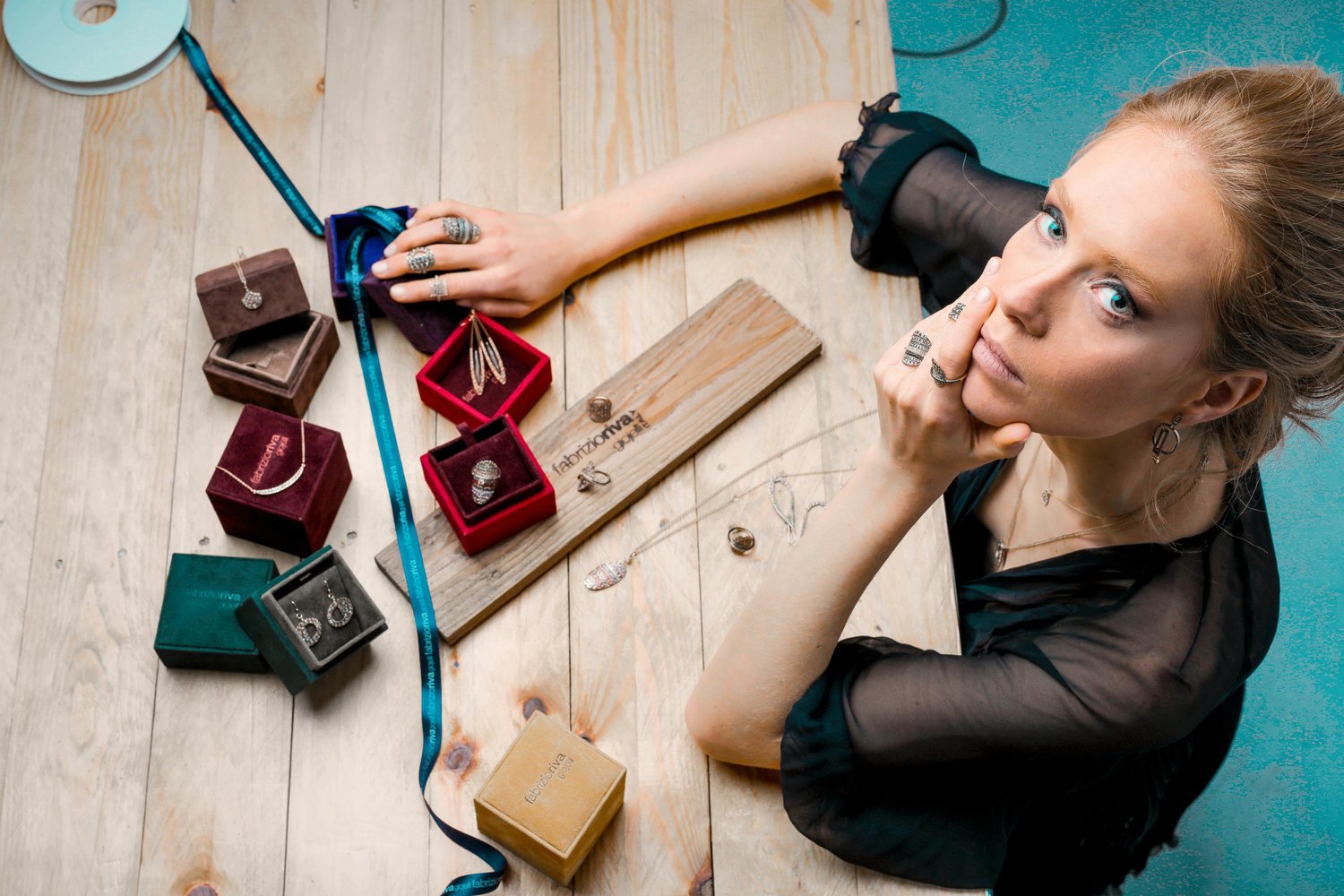 a young frustrated business owner looking upwards towards the camera, sitting at her craftwork desk