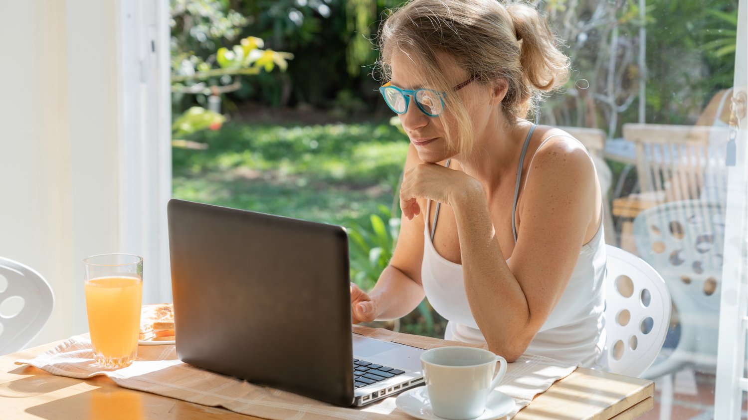 Health coach working on a laptop at a sunny kitchen table, planning organic traffic strategies to promote her lead magnet.