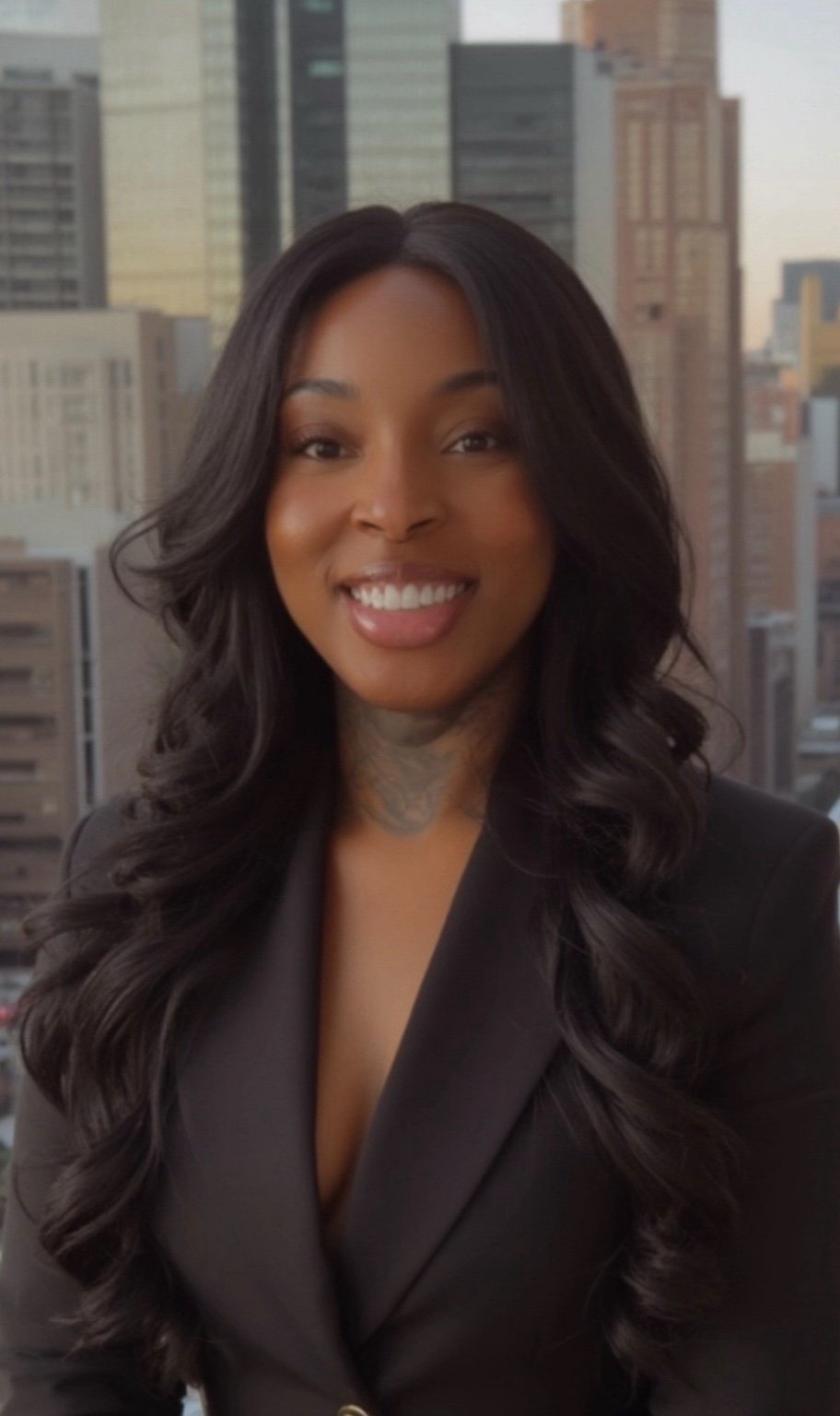 Dr. Lleya R. H. Gordon, founder of Eros Reclusion, smiling confidently in a black blazer against a city skyline — representing financial literacy, empowerment, and real estate success.