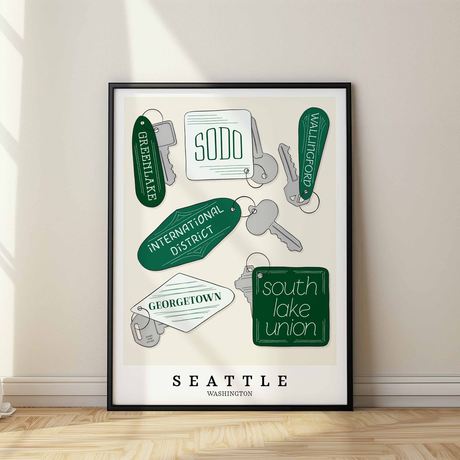 A framed picture of Seattle neighborhoods drawn in various lettering styles on key fobs. Artwork has a green and white color scheme